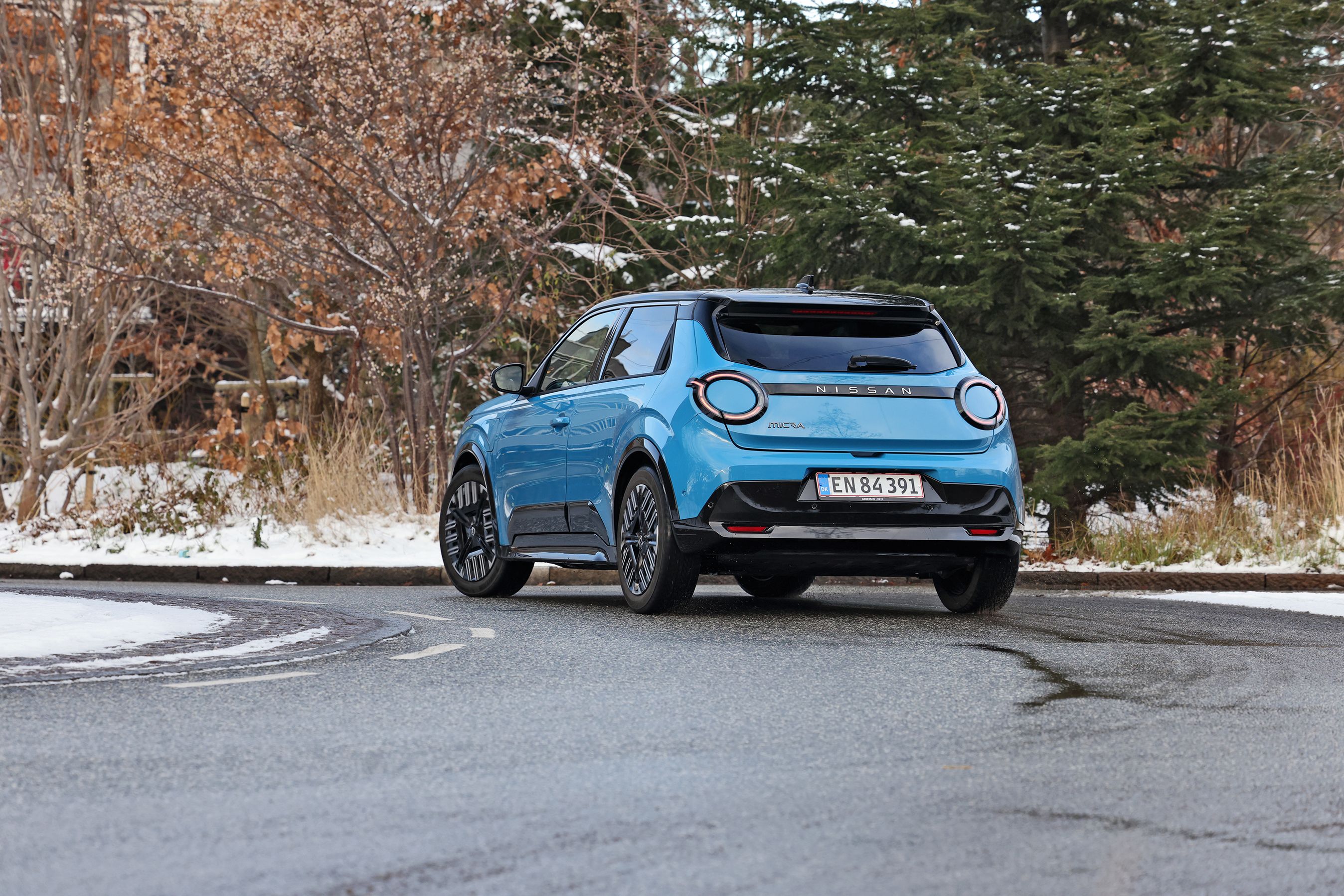 Blå Nissan Micra set bagfra, mens den kører i et sving