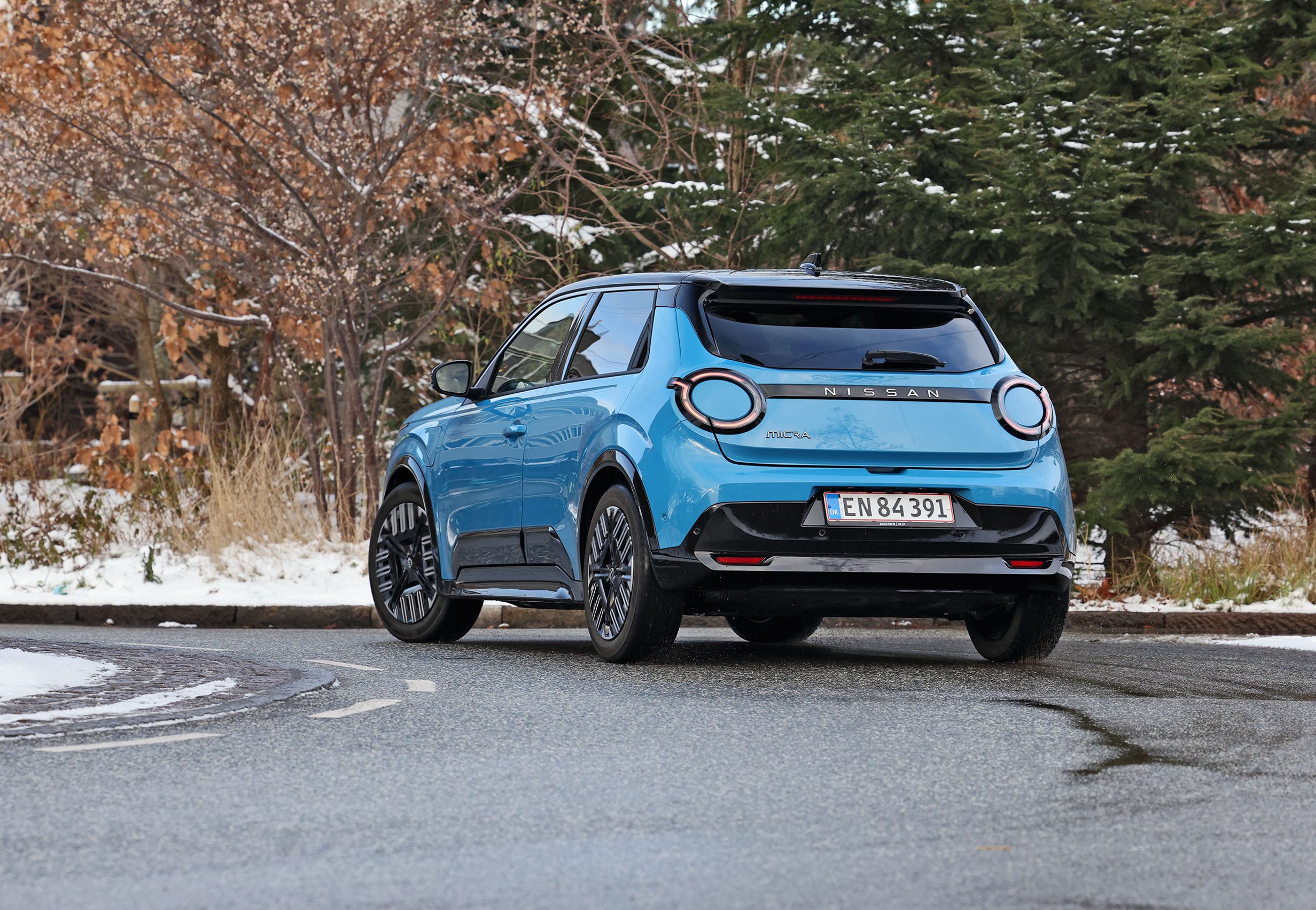 Blå Nissan Micra set bagfra, mens den kører i et sving