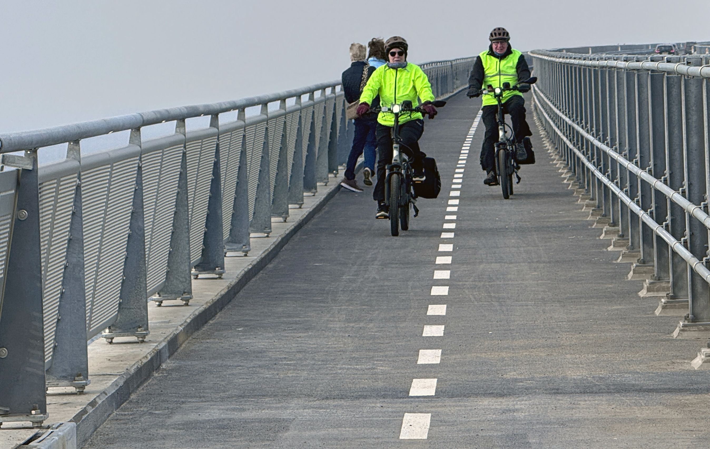 Cyklister med gul vest på sti på bro.