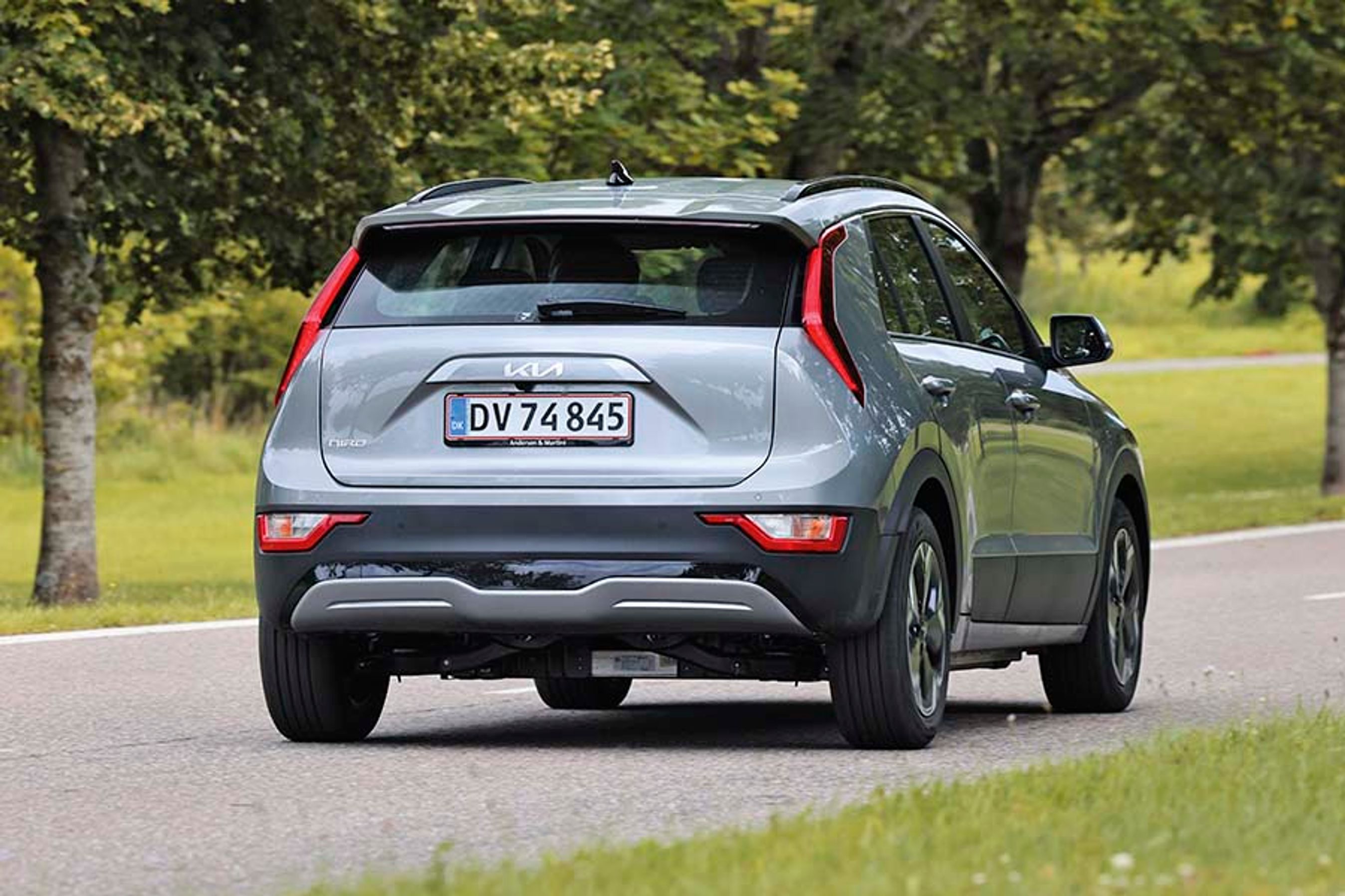 Elbilen Kia Niro set bagfra, mens den kører ned ad en allé.