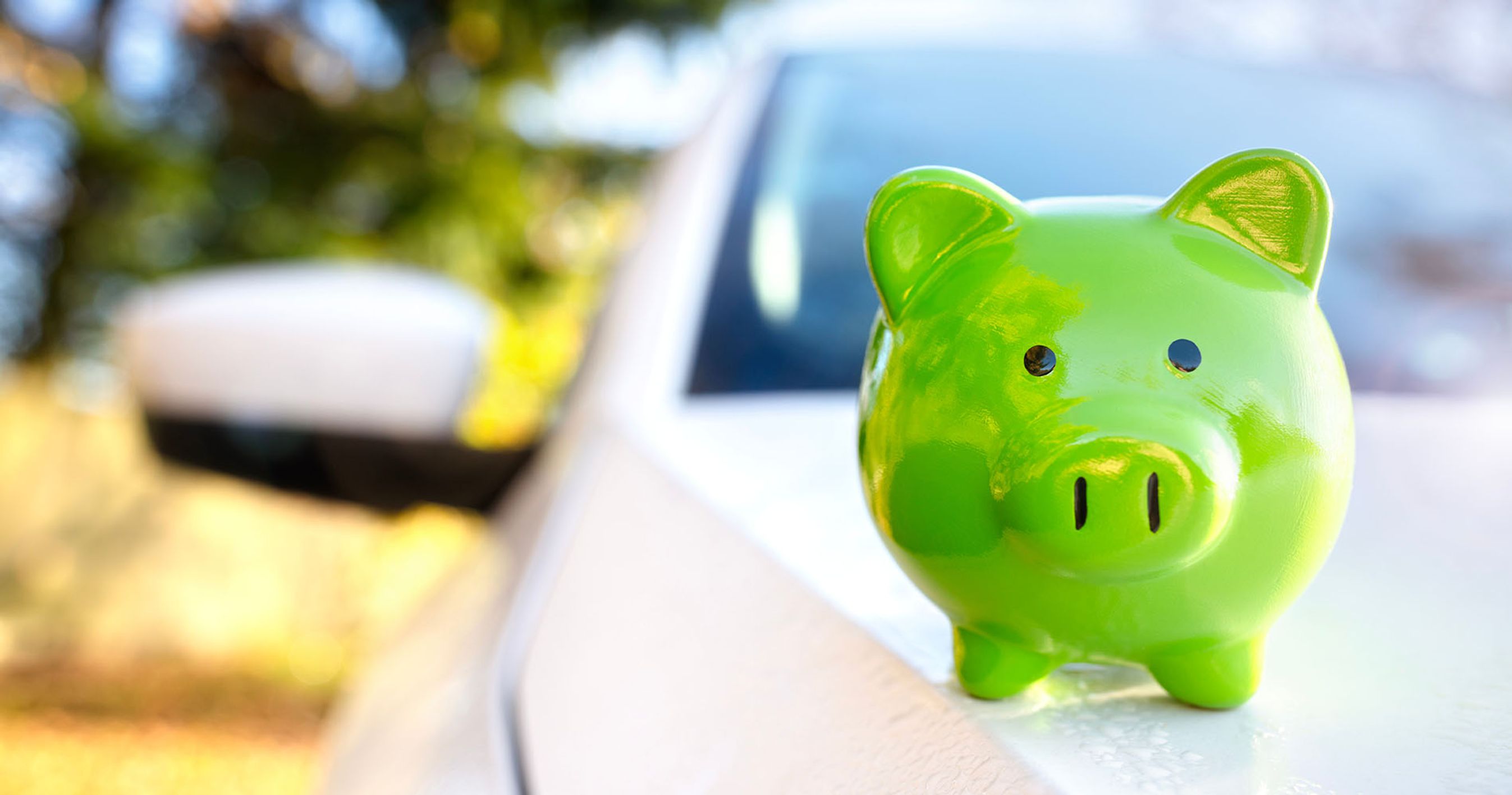 Grøn sparegris står på kølerhjelmen på en hvid bil