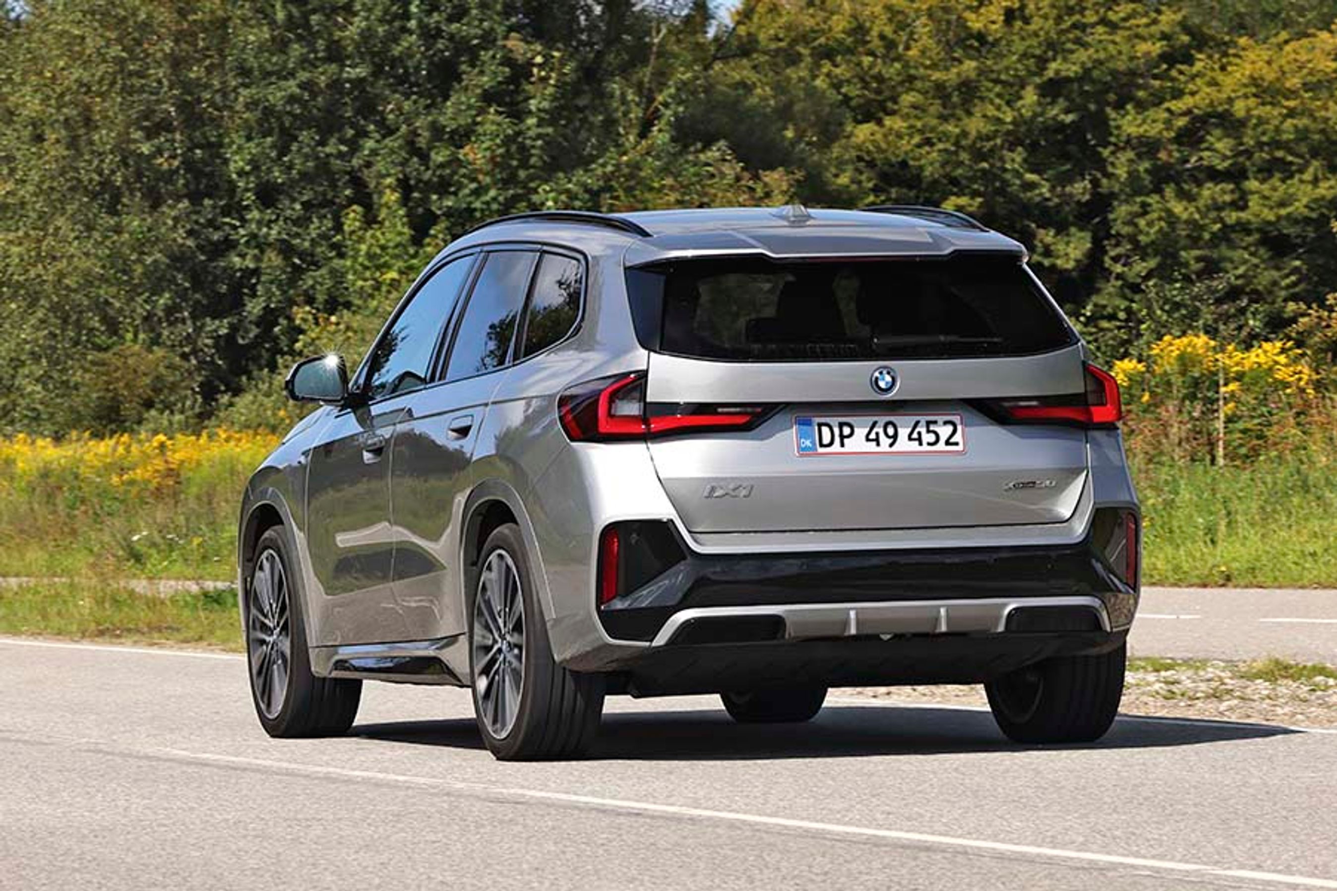 BMW iX1 set bagfra, mens den kører på landevej.
