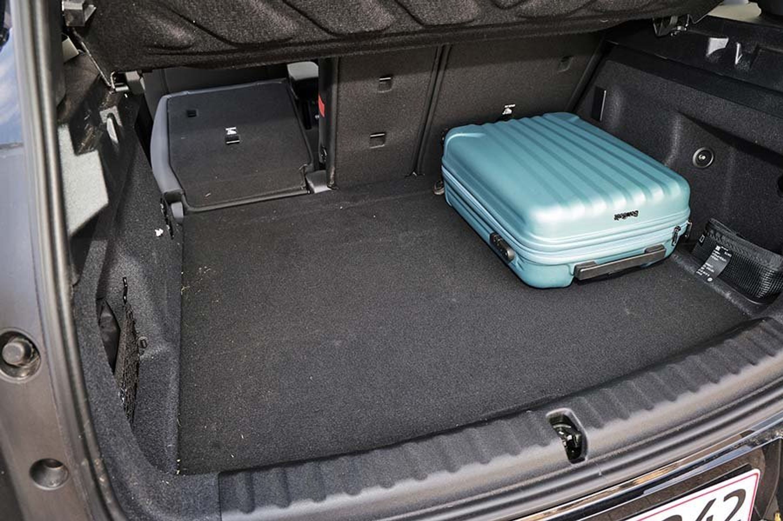 Bagagerum med blå kufferti i en Mini Countryman. Ryglæn på det ene bagsæde er lagt ned.