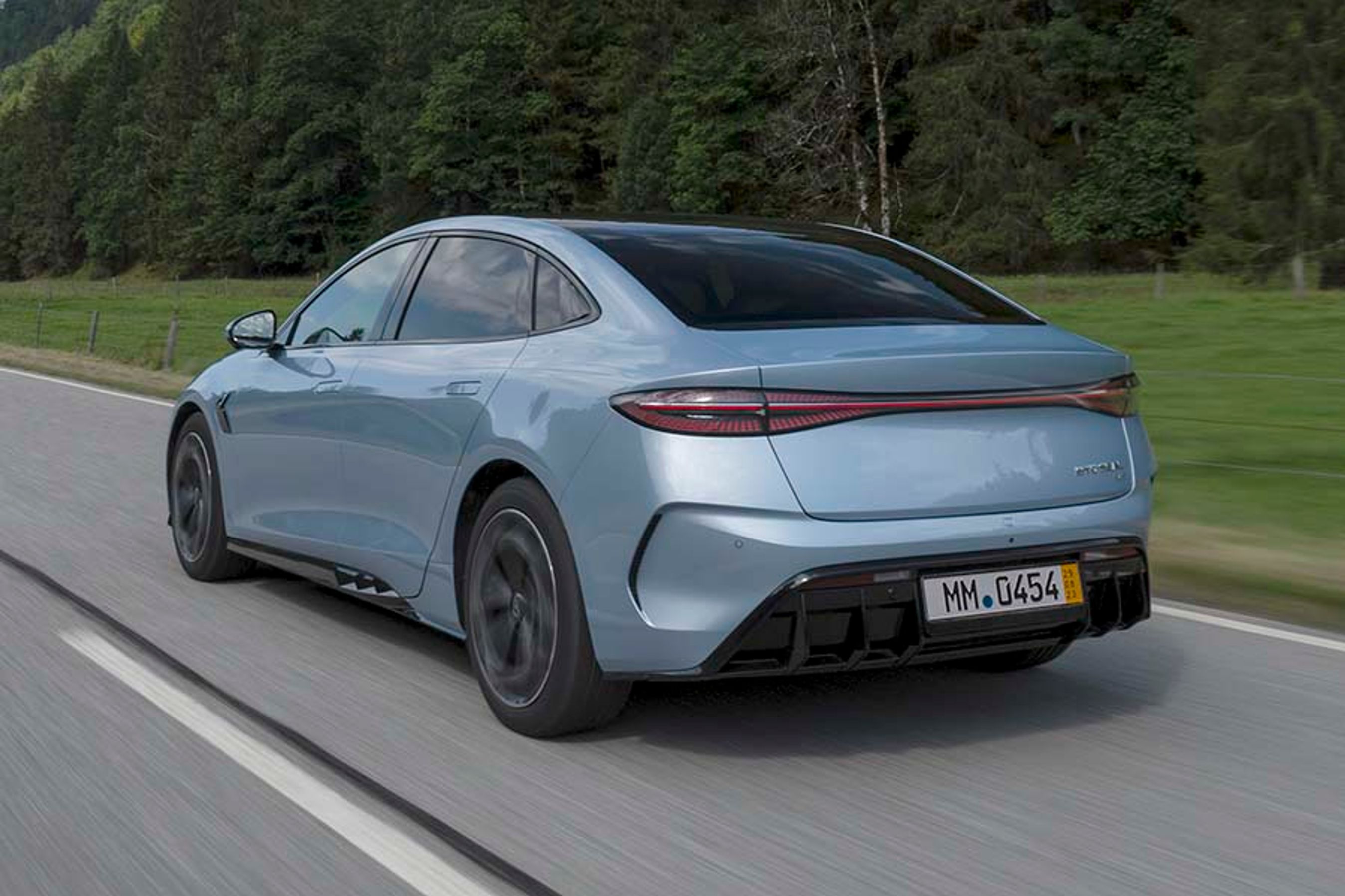 BYD Seal set bagfra, mens den kører på en landevej med træer i baggrunden