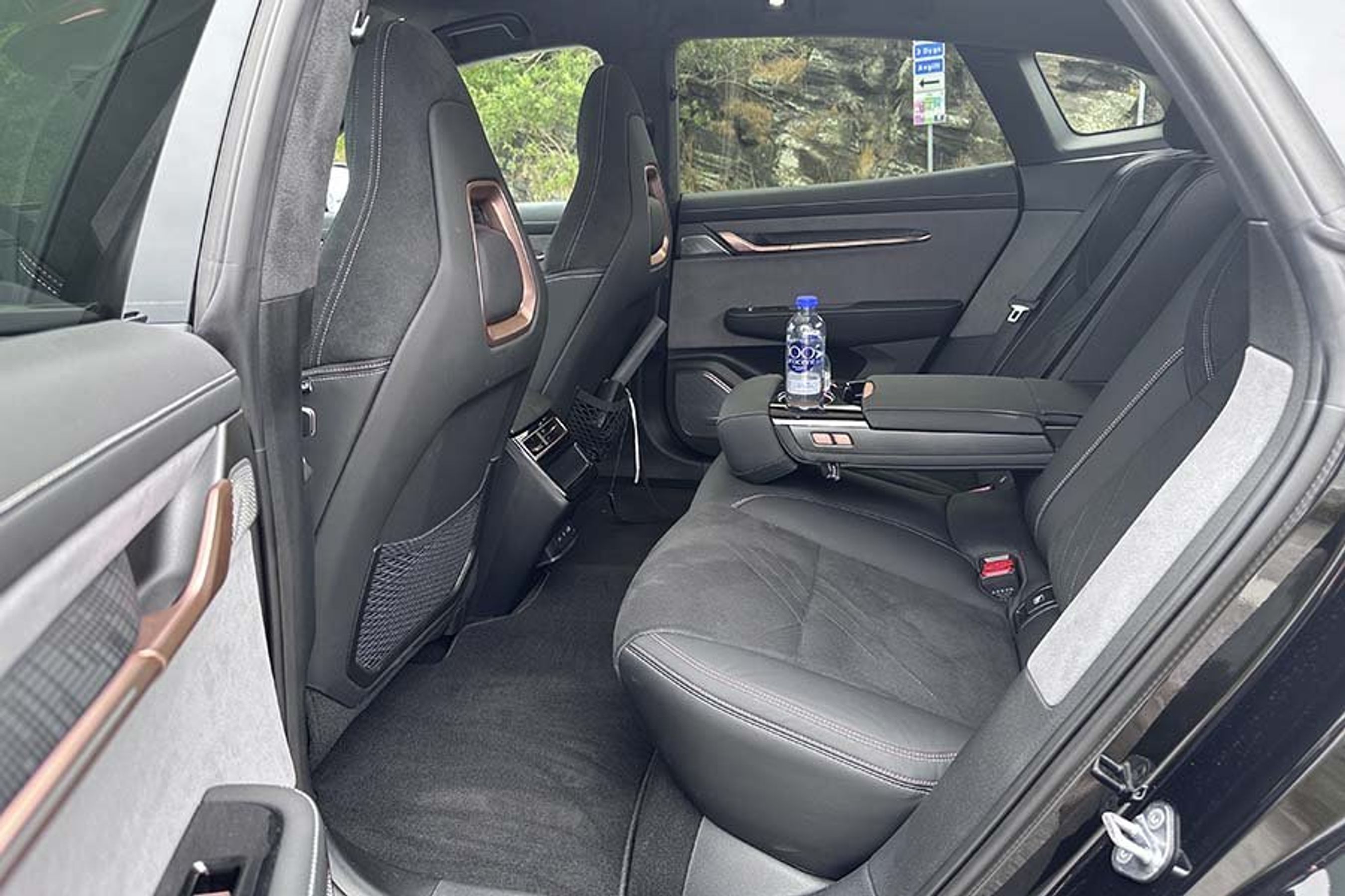 Bagsædet i en Zeekr 001 elbil, hvor armlænet er slået ned, så der kan stå vandflasker i kopholderen.