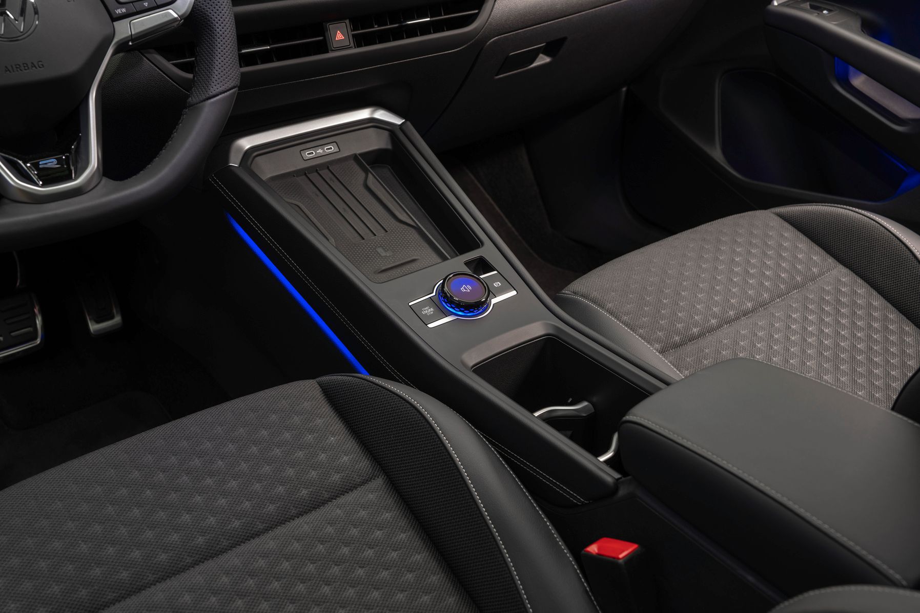 Detaljebillede i kabinen på VW T-Roc hvor man kan se mobillader samt volumenknap.