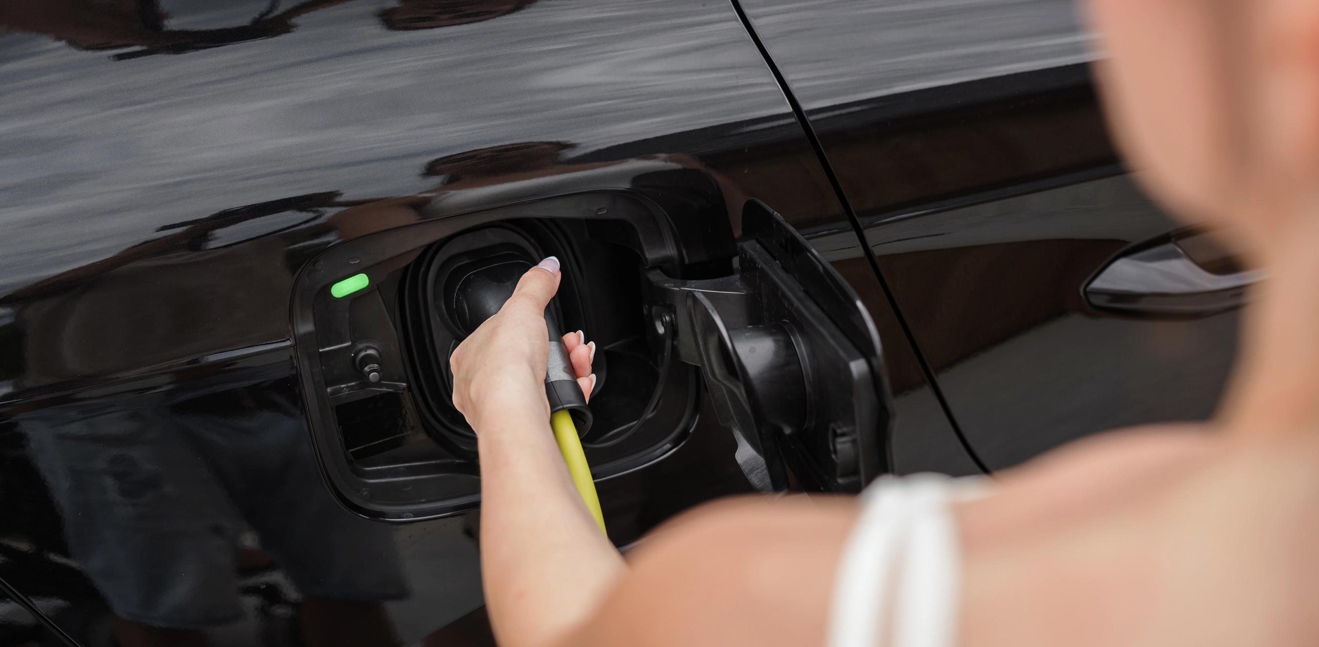 Kvinde sætter ladestik i en bil