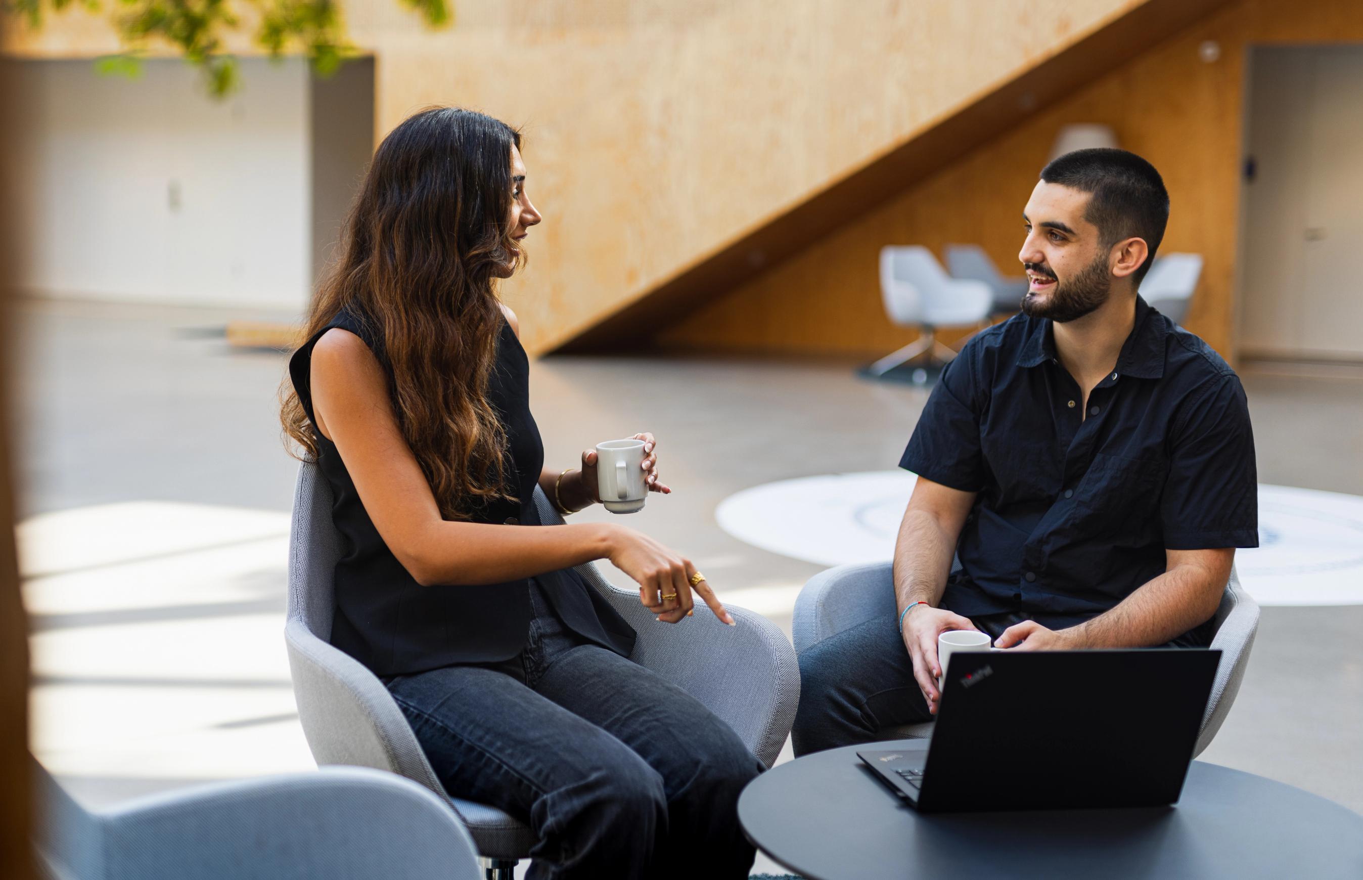 To FDM medarbejdere taler sammen ved et mødebord