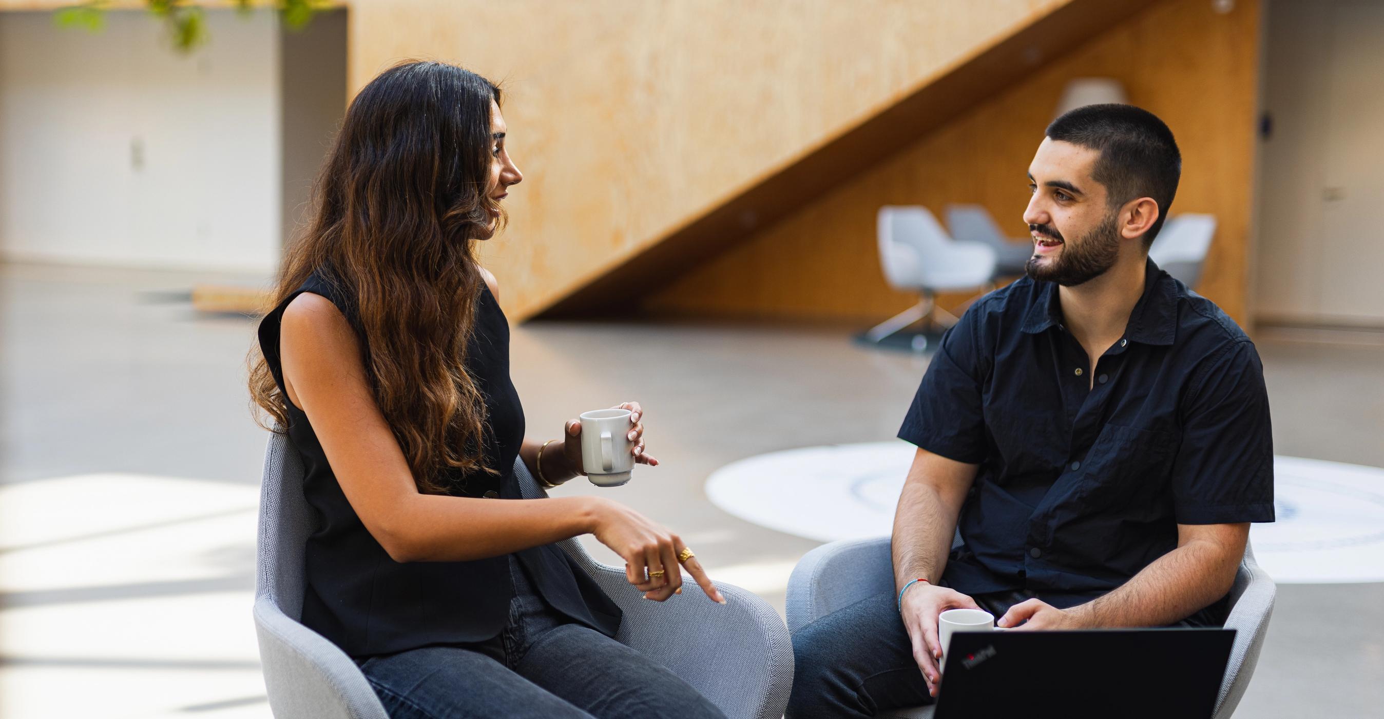 To FDM medarbejdere taler sammen ved et mødebord