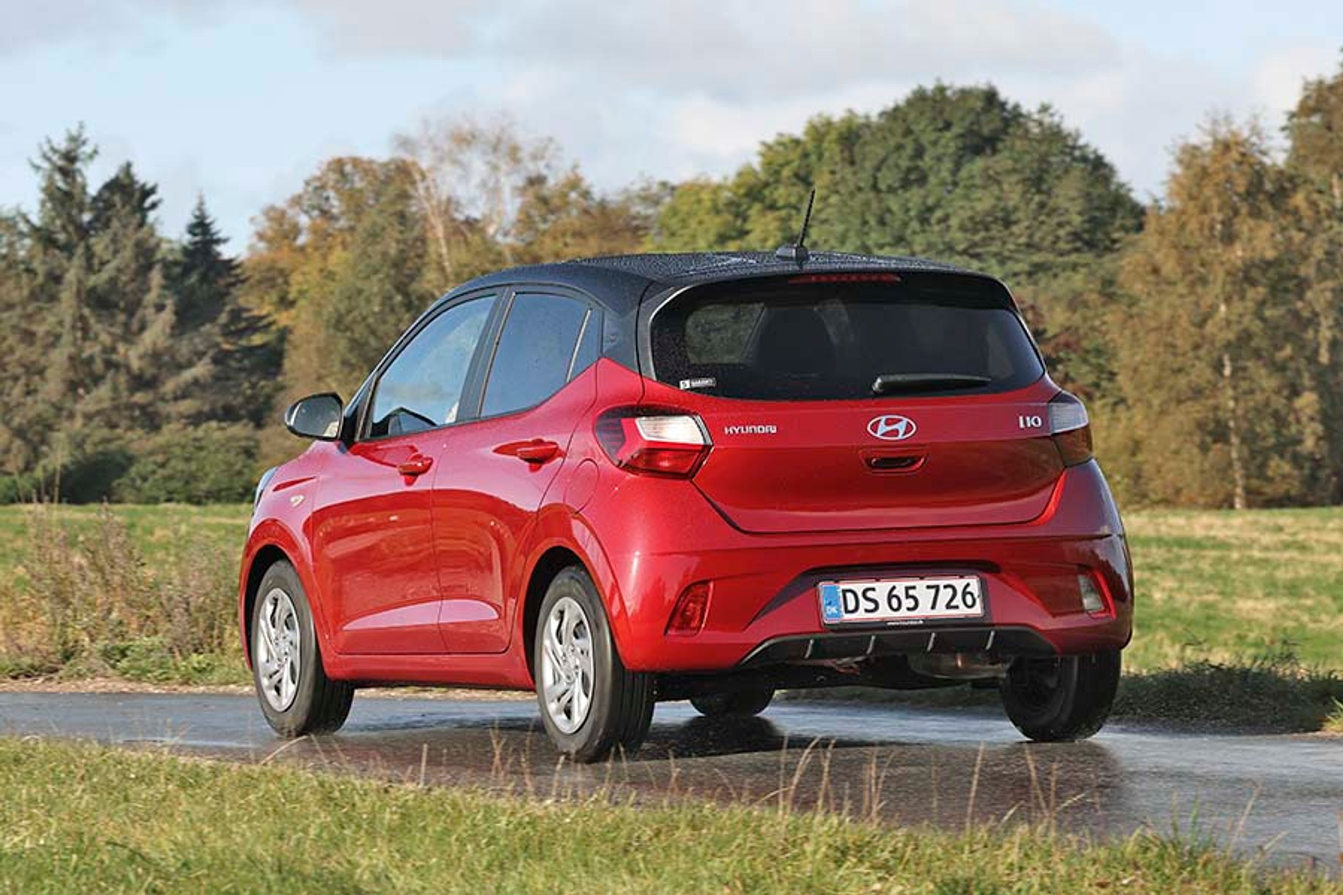 En rød Hyundai I10 set bagfra på en landevej