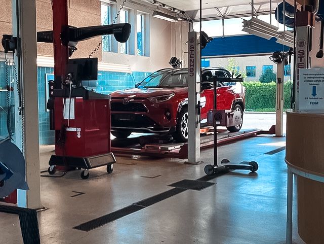 Rød bil holder klar på liften til bilsyn og biltest i Vejle