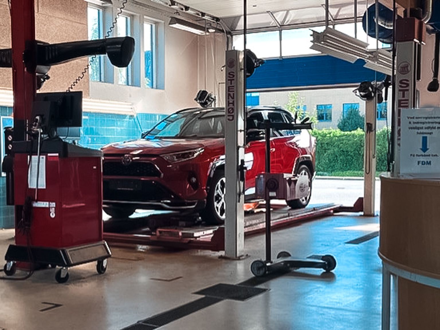 Rød bil holder klar på liften til bilsyn og biltest i Vejle