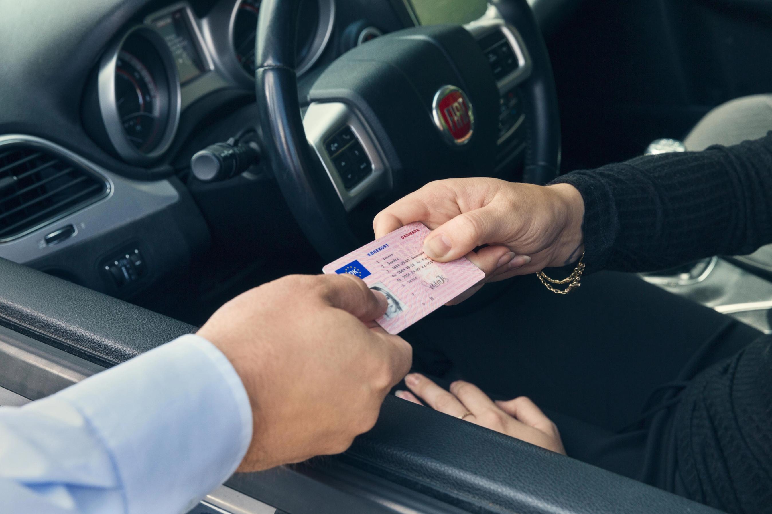 Kørekort rækkes ud af bilvindue.