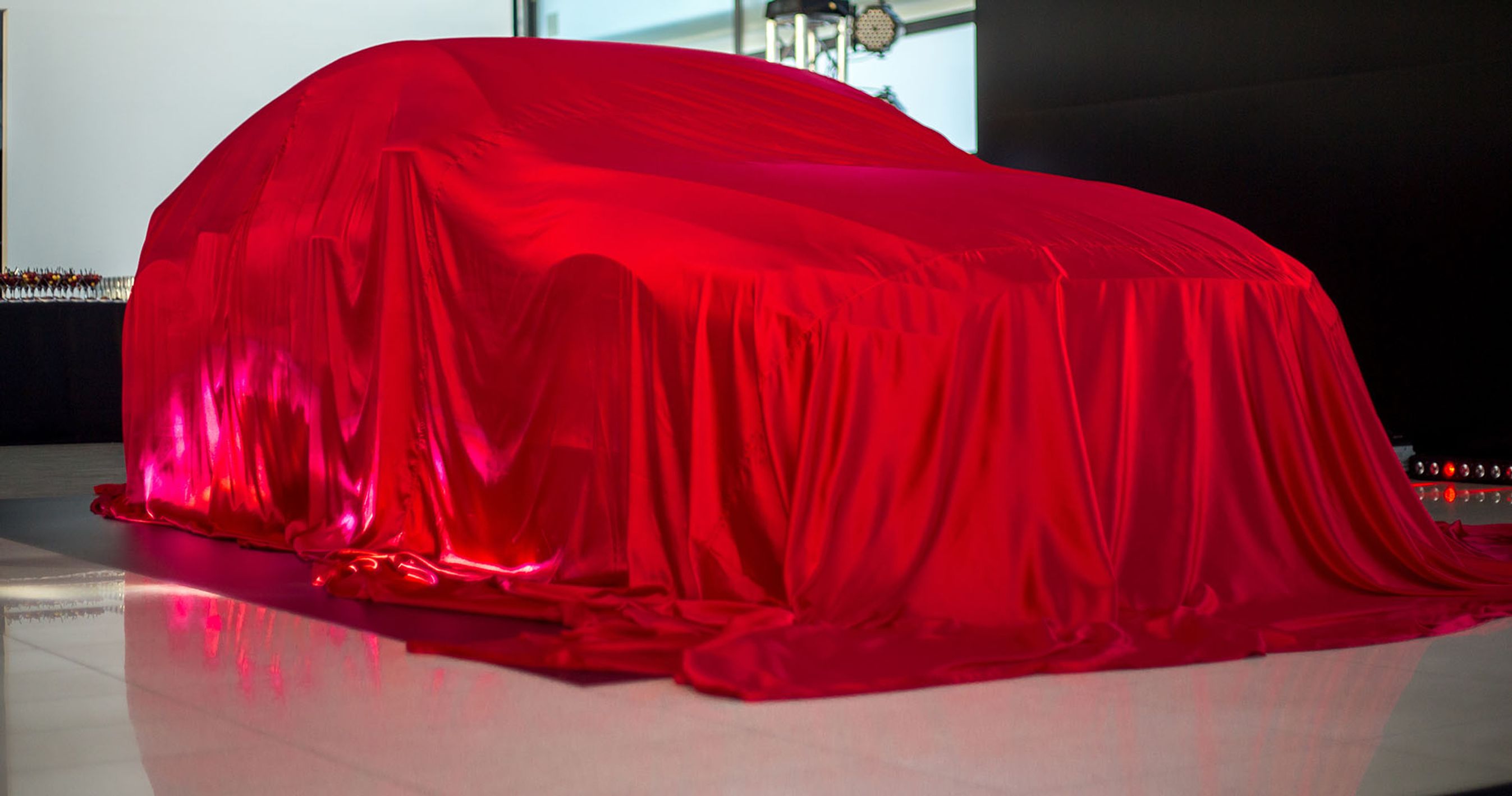 Bil dækket med rødt tæppe. Holder i en bilforretning.