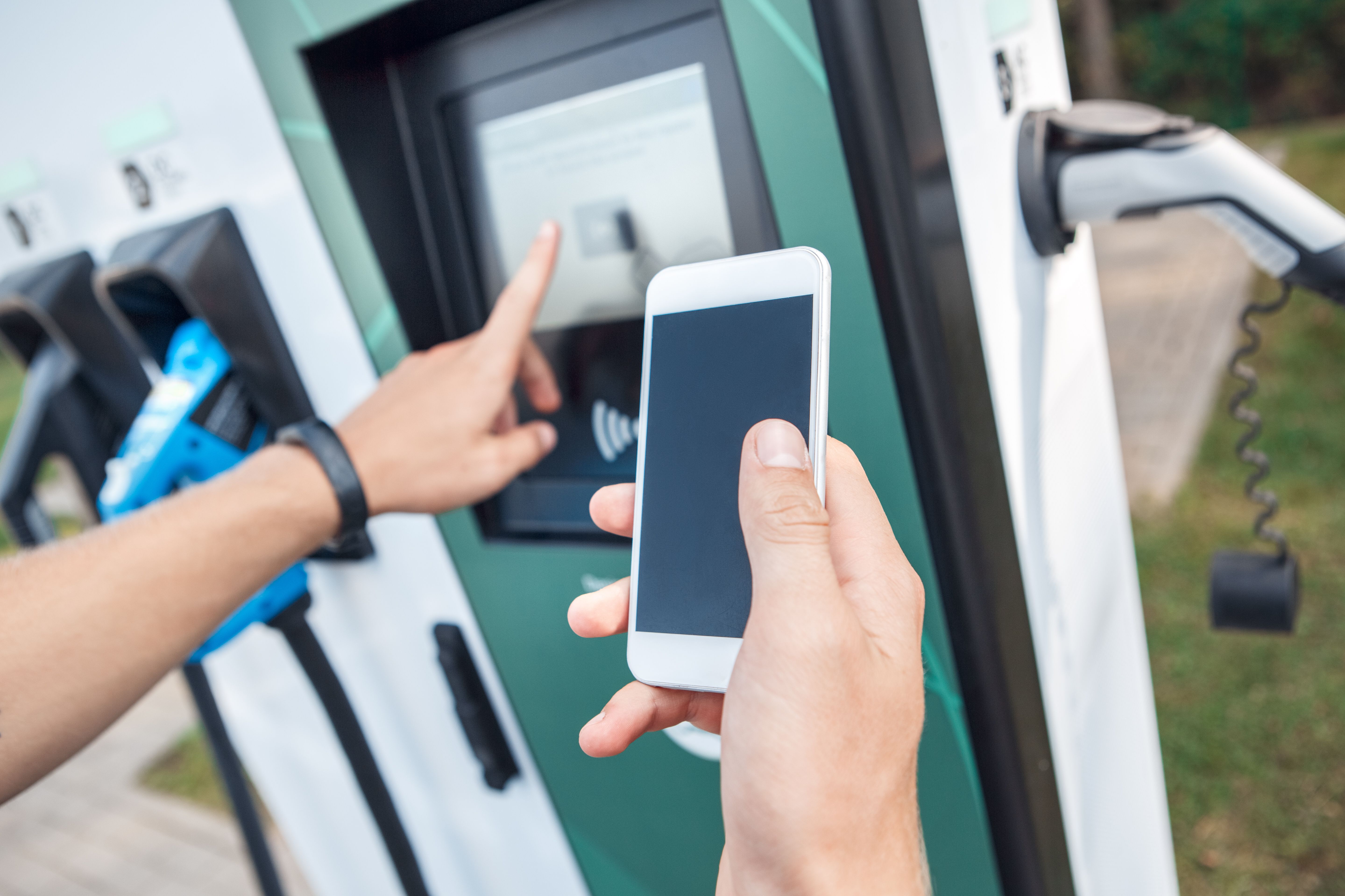 Person står med telefon og betaler for opladning