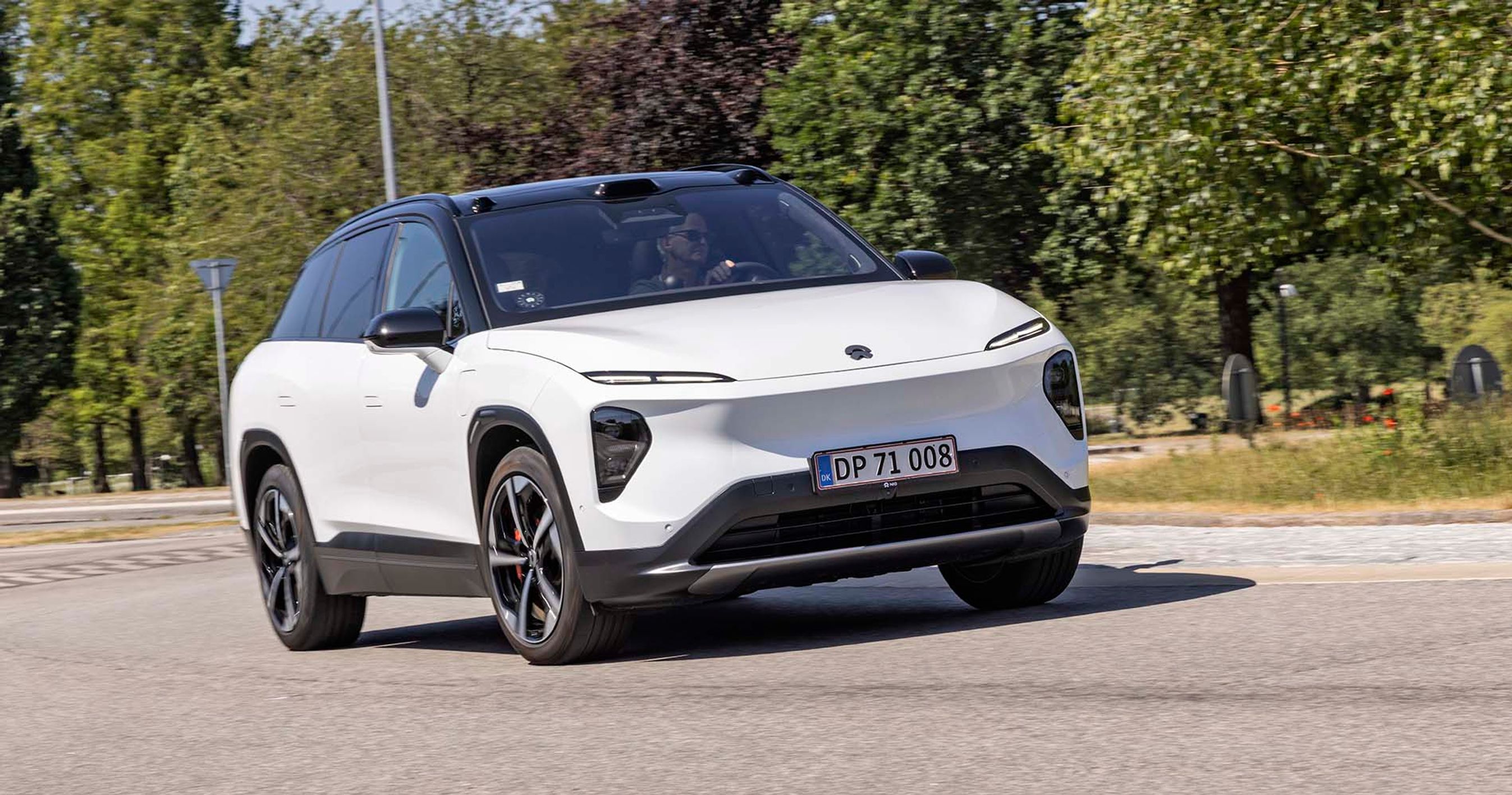 Hvis Nio EL7 elbil kører på vej med træer i baggrunden