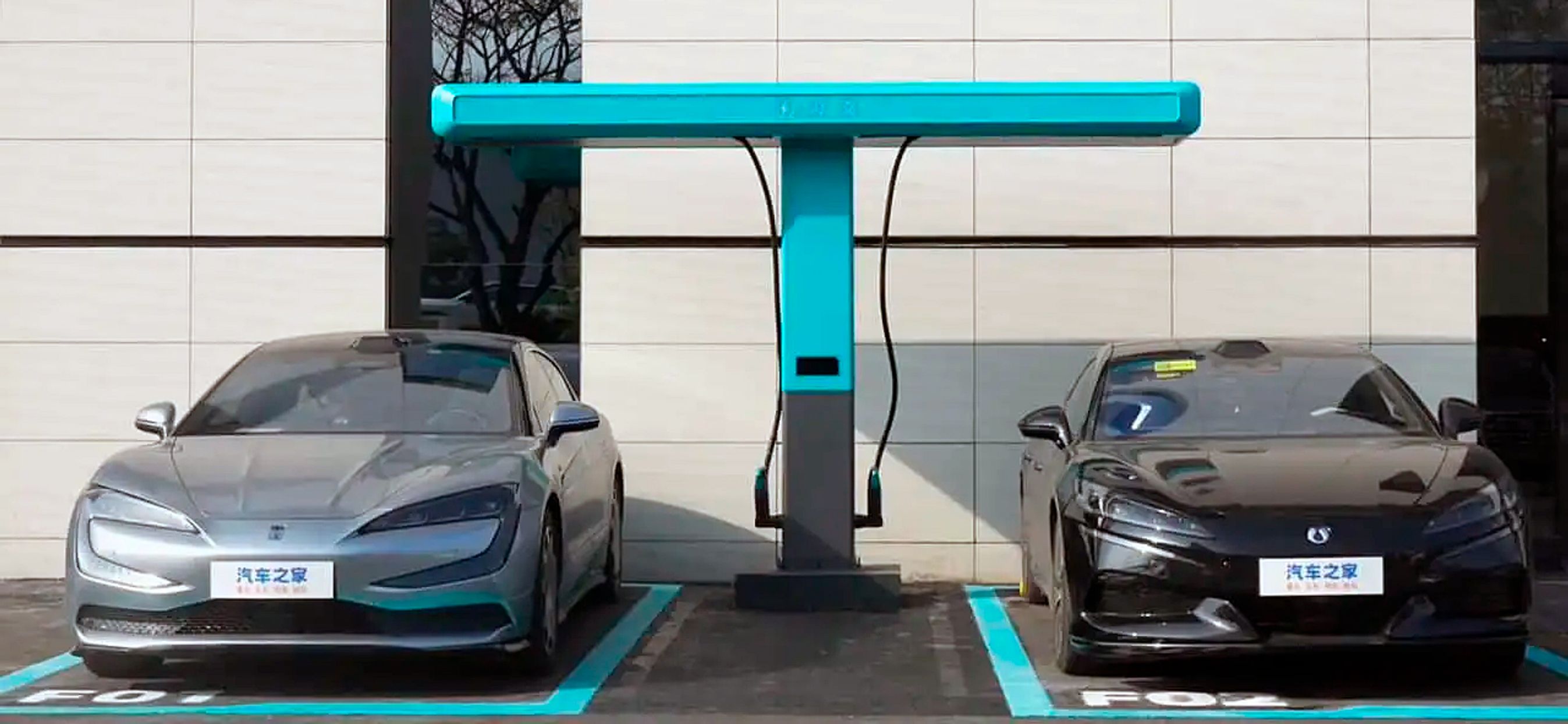 to biler holder under turkis bjælke med ladekabler hængende ned. 