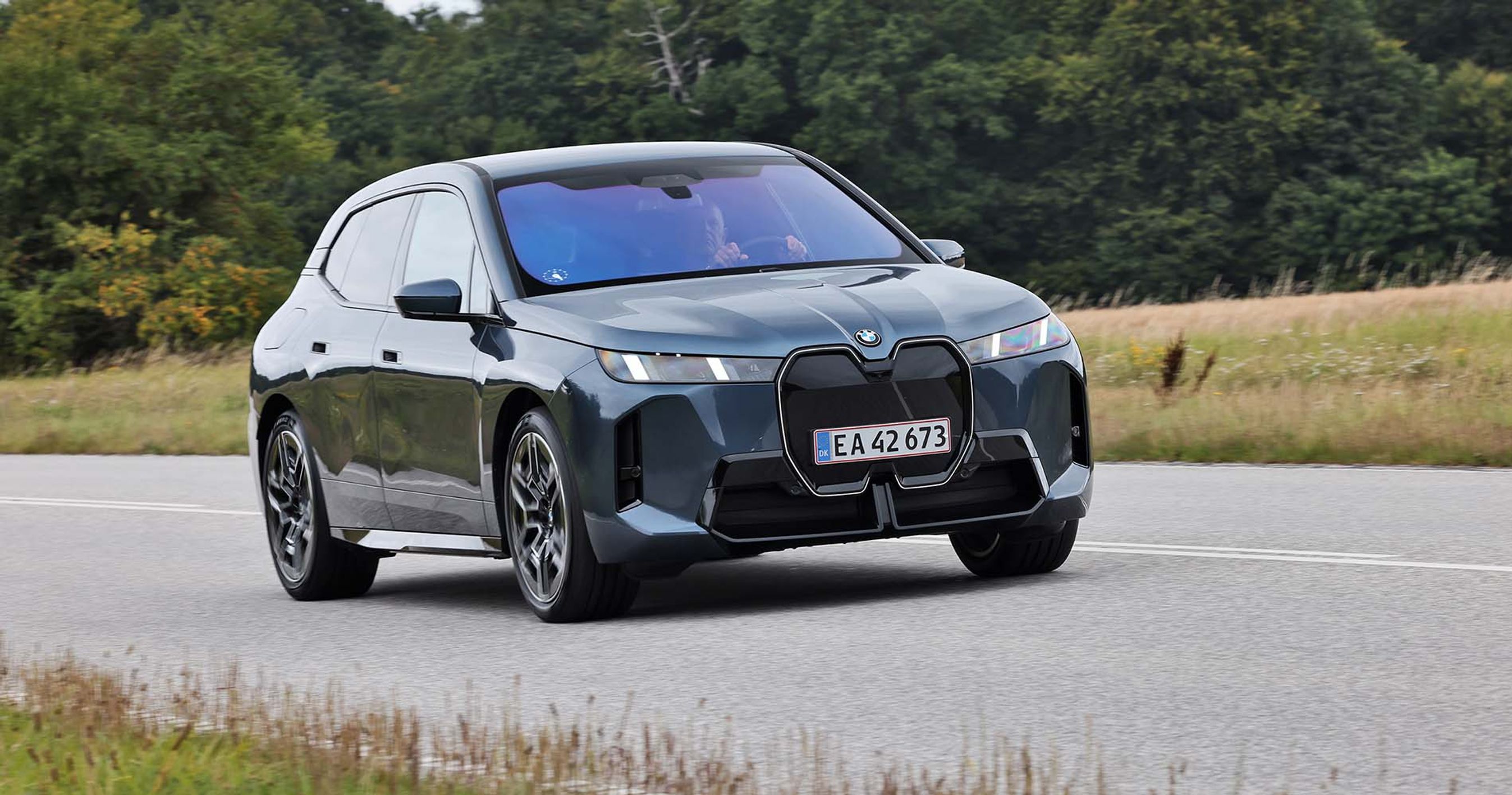 BMW iX set skråt forfra, mens den kører på en landevej