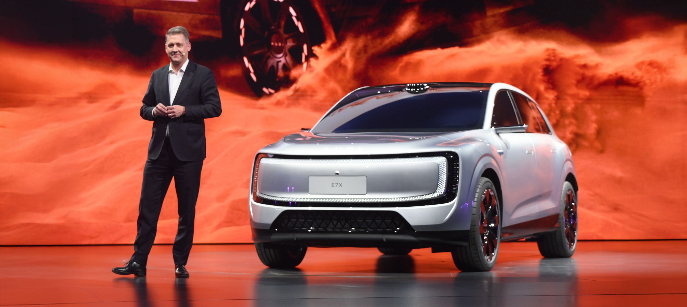 Person og sølvgrå Audi på scene med flammende rød baggrund.