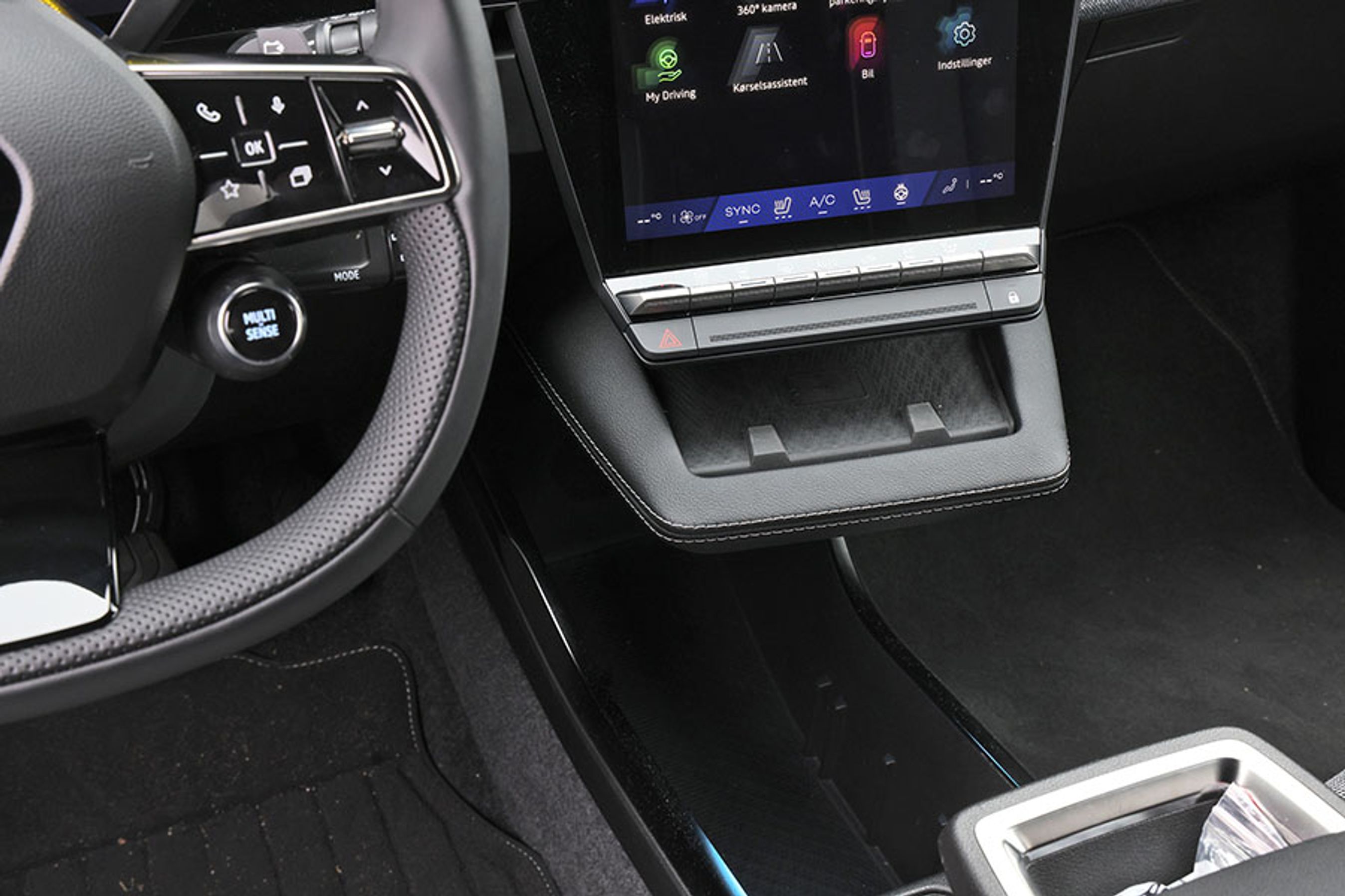 En lille holder til mobilen er smart. Den er nem at finde og holder fint på telefonen. Har du lange ben, rammer knæet lige ind i kanten. Knap så behageligt.