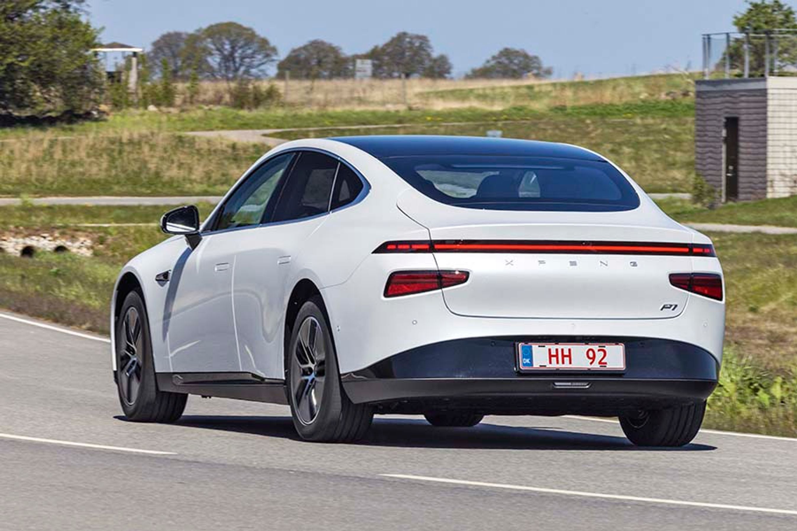 Xpeng P7 set bagfra, mens den kører i et sving på en landevej