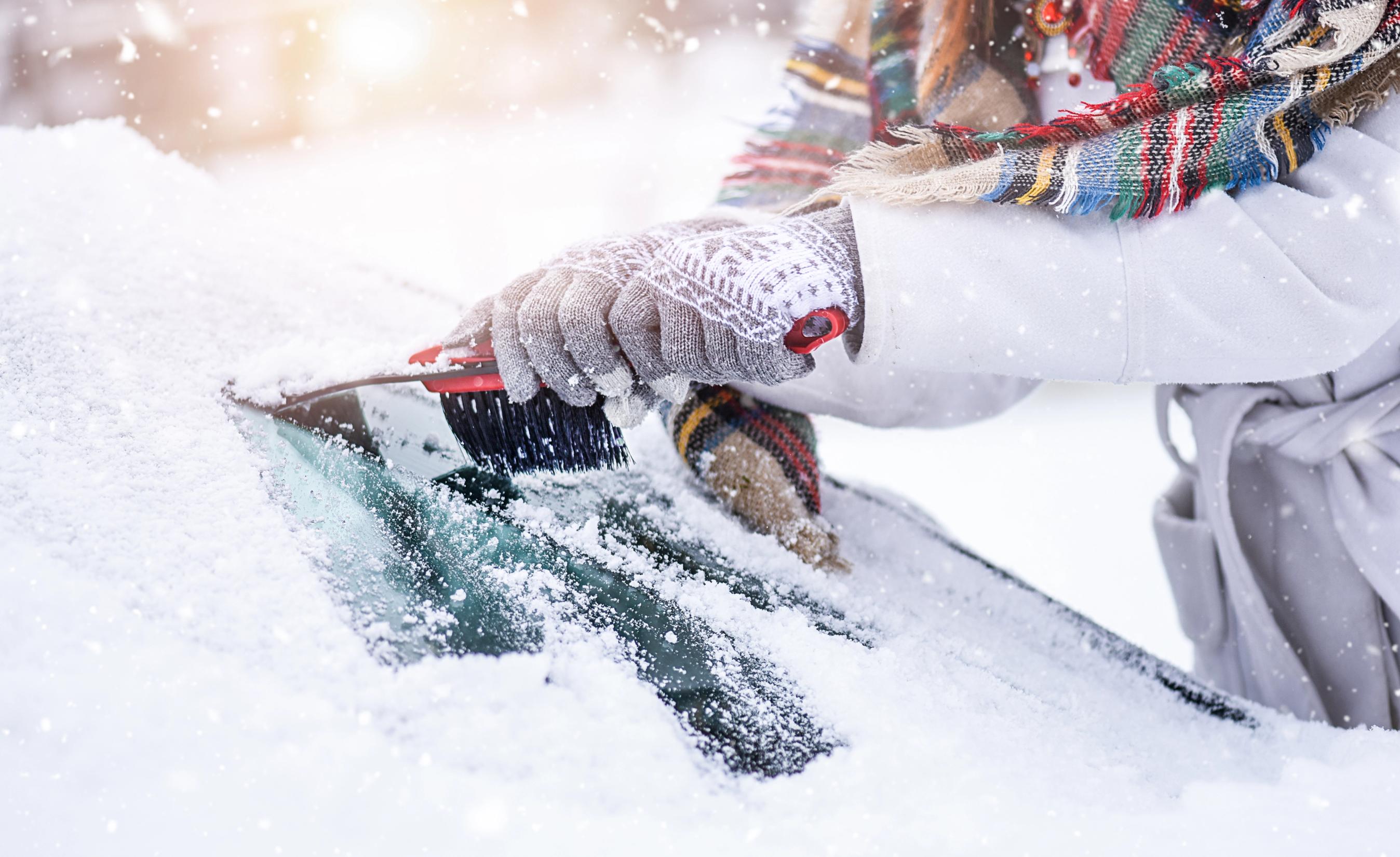 Is og sne fjernes fra en forrude på en bil om vinteren.