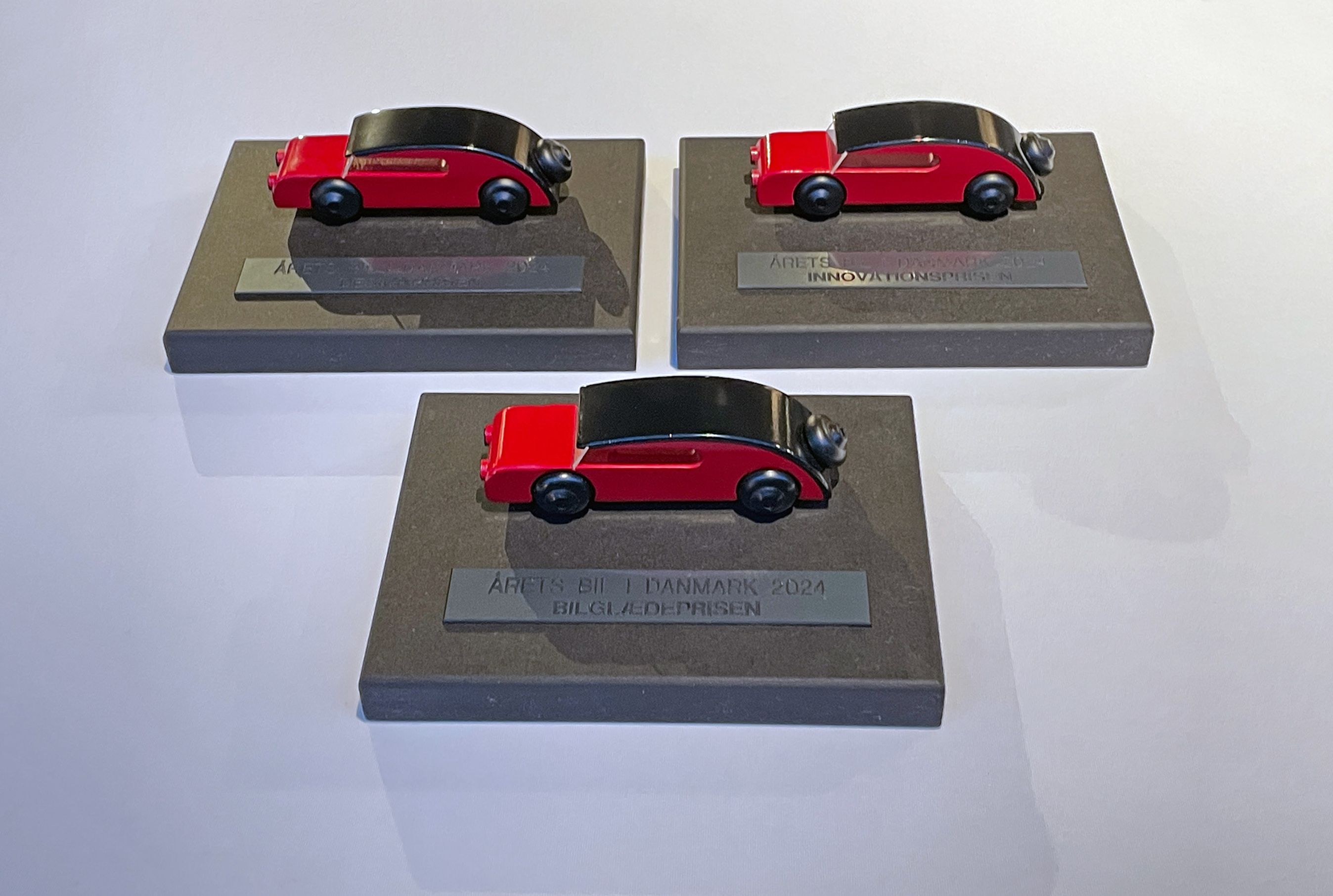 tre modelbiler på hvid dug.