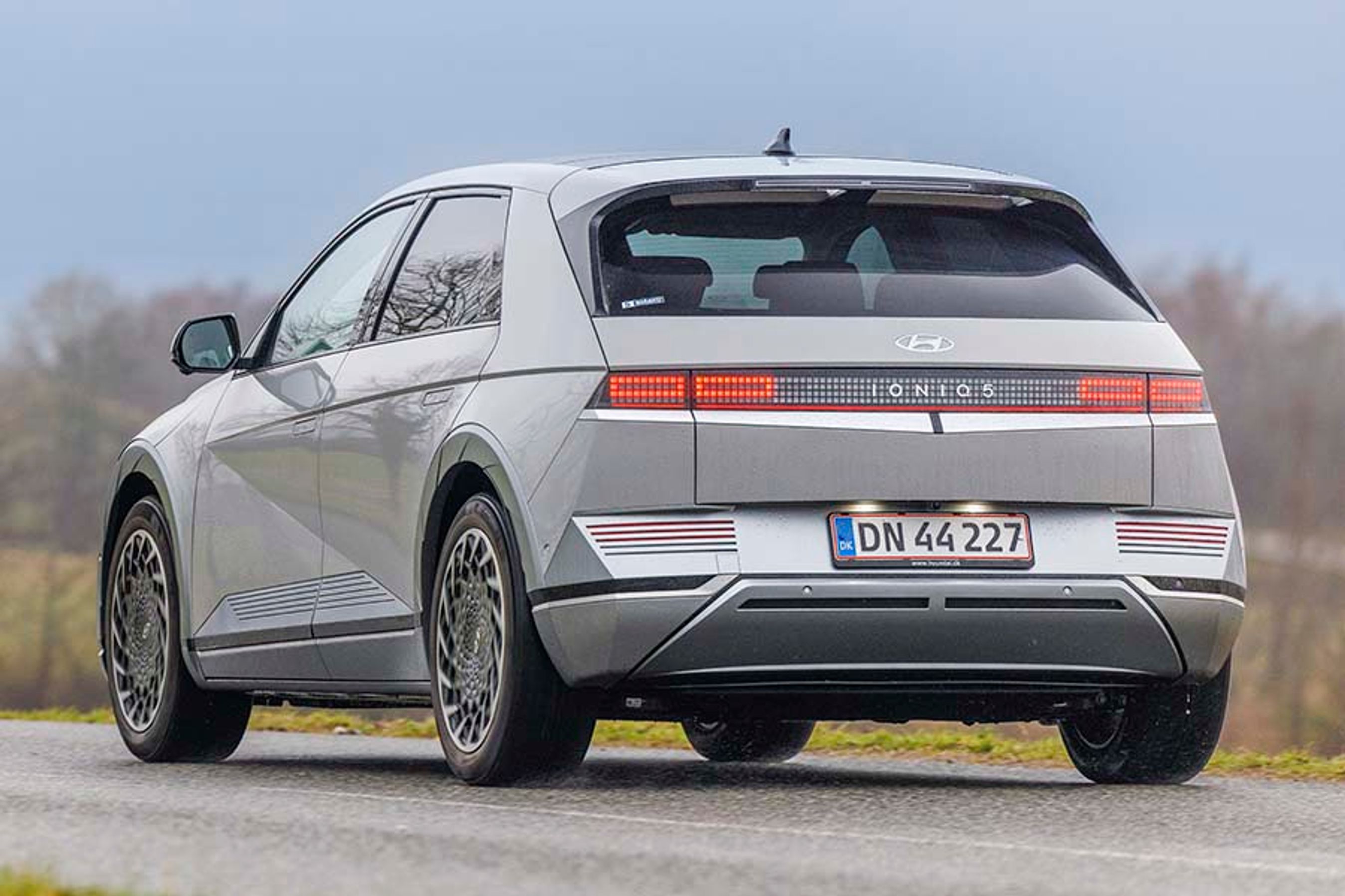 Hyundai Ioniq 5 set bagfra, mens den kører ud ad en landevej i gråvejr