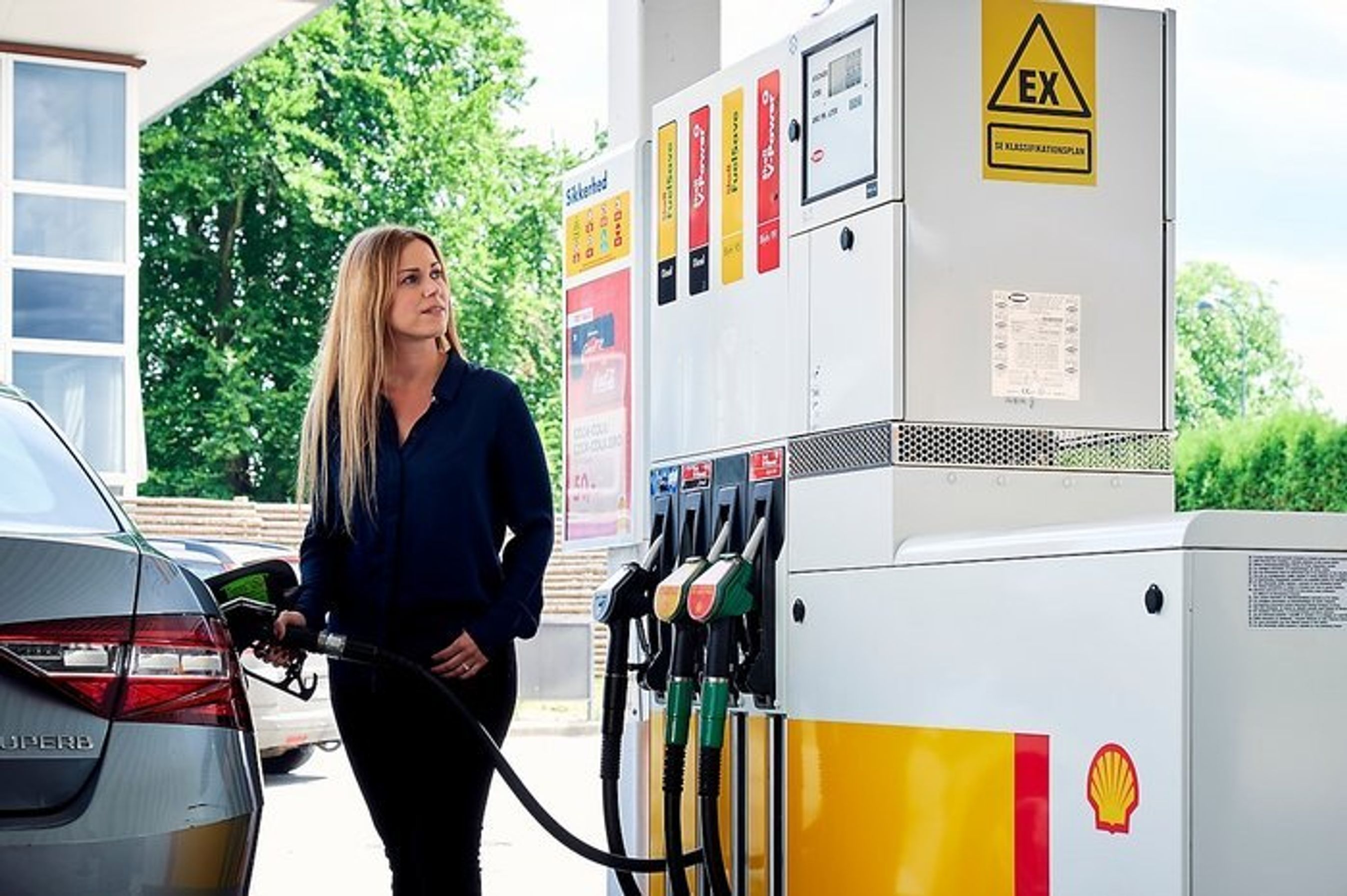 Kvinde tanker benzin på Shell-station.