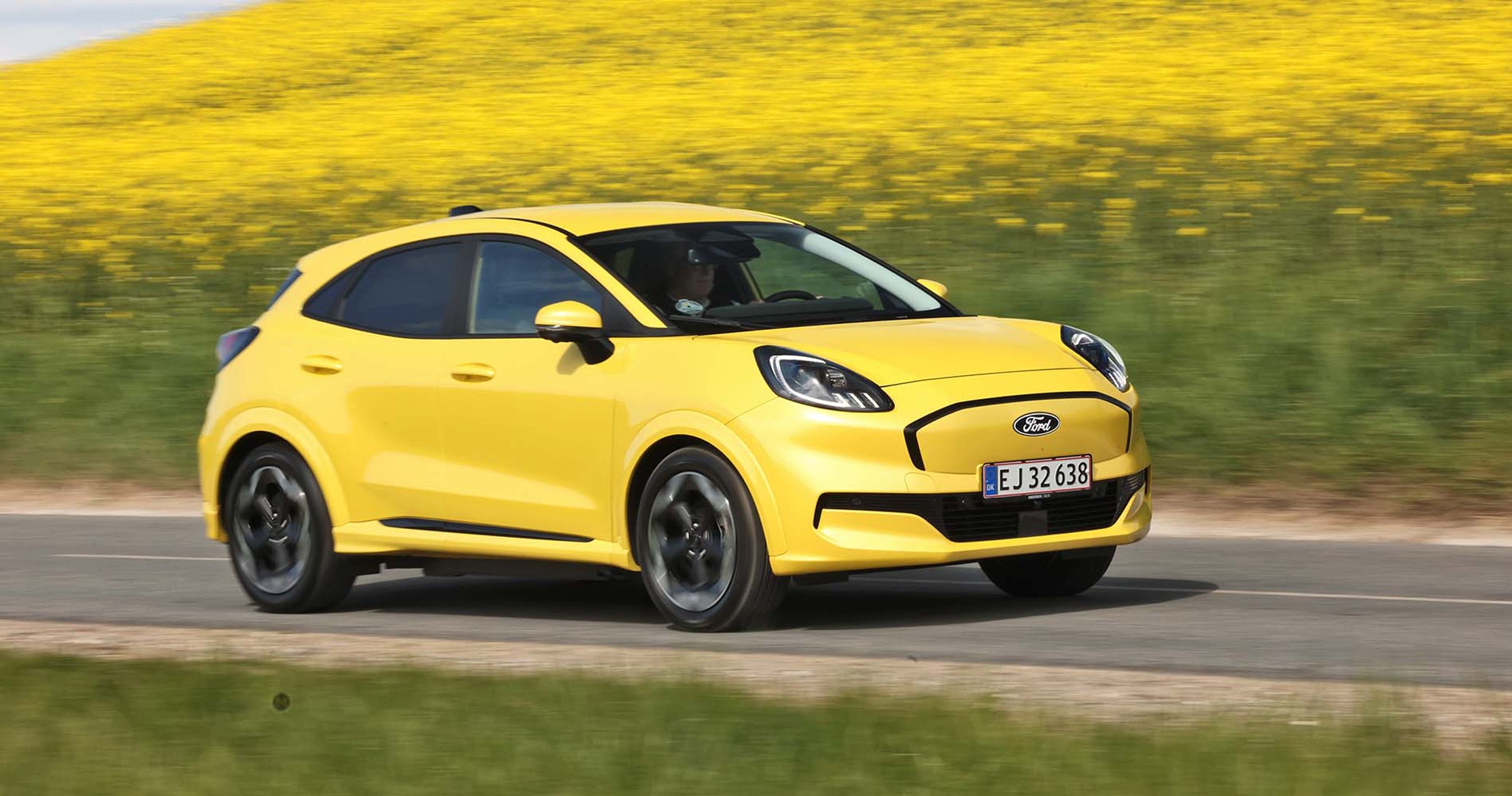 Gul Ford Puma kører på vej med rapsmarker i baggrunden