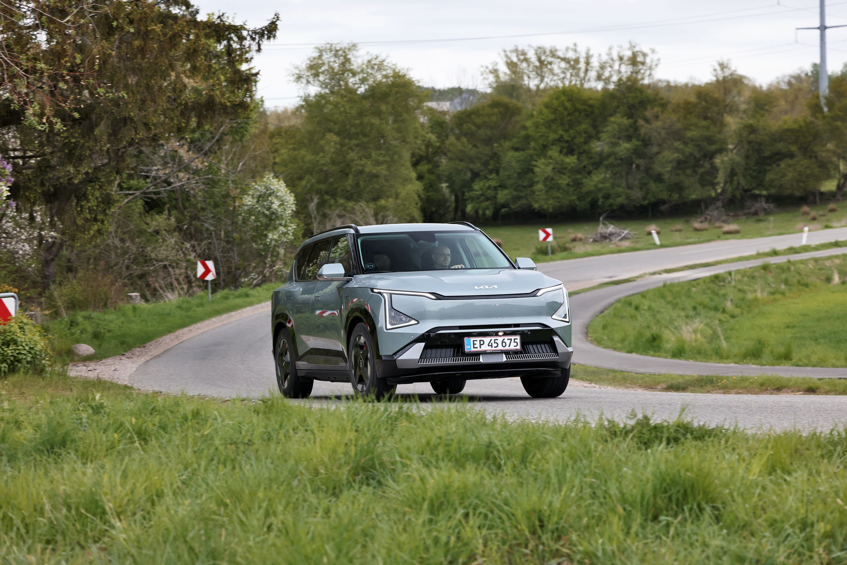 Kia EV5 Long Range Prestige 2026 kører på en landevej. 