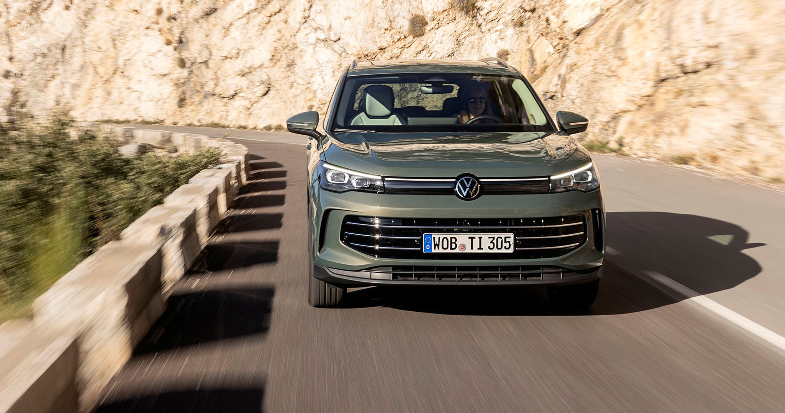 En VW Tiguan kører ud af et sving på en bjergvej med klipper i baggrunden