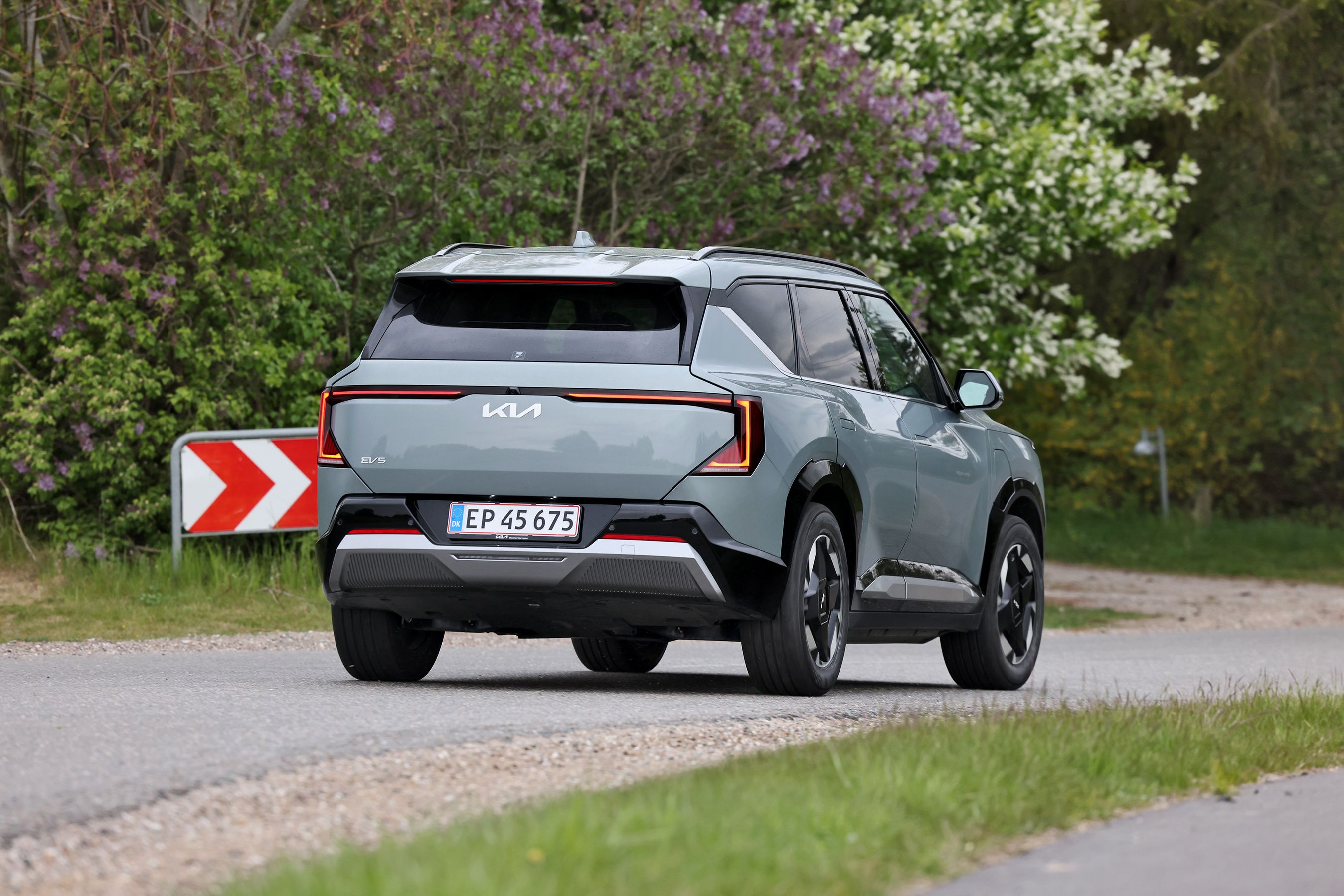 Kia EV5 Long Range Prestige 2026 set bagfra på landevej med vejskilt i baggrunden. 