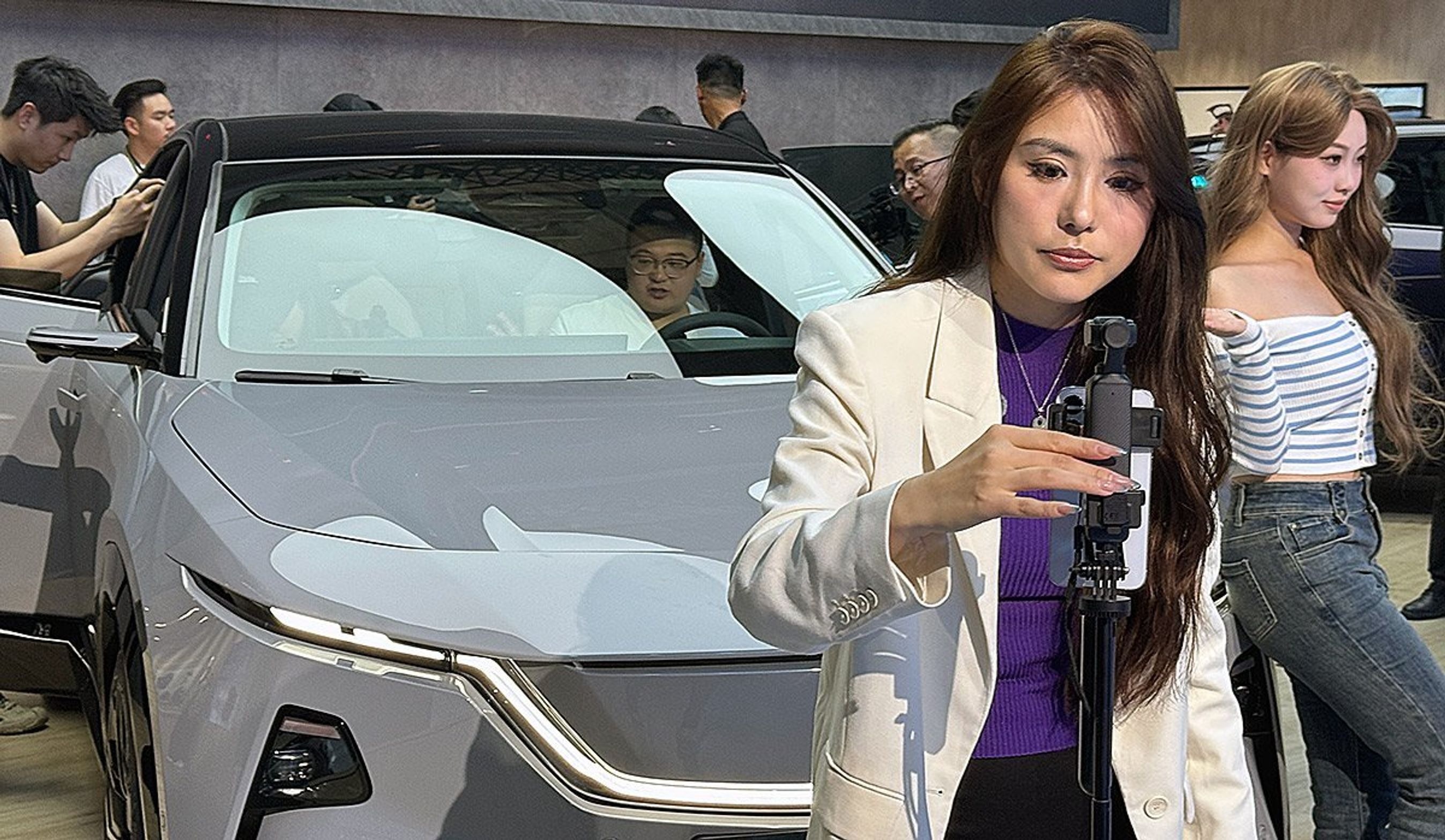 Kvinder med kamera foran bil på biludstilling.