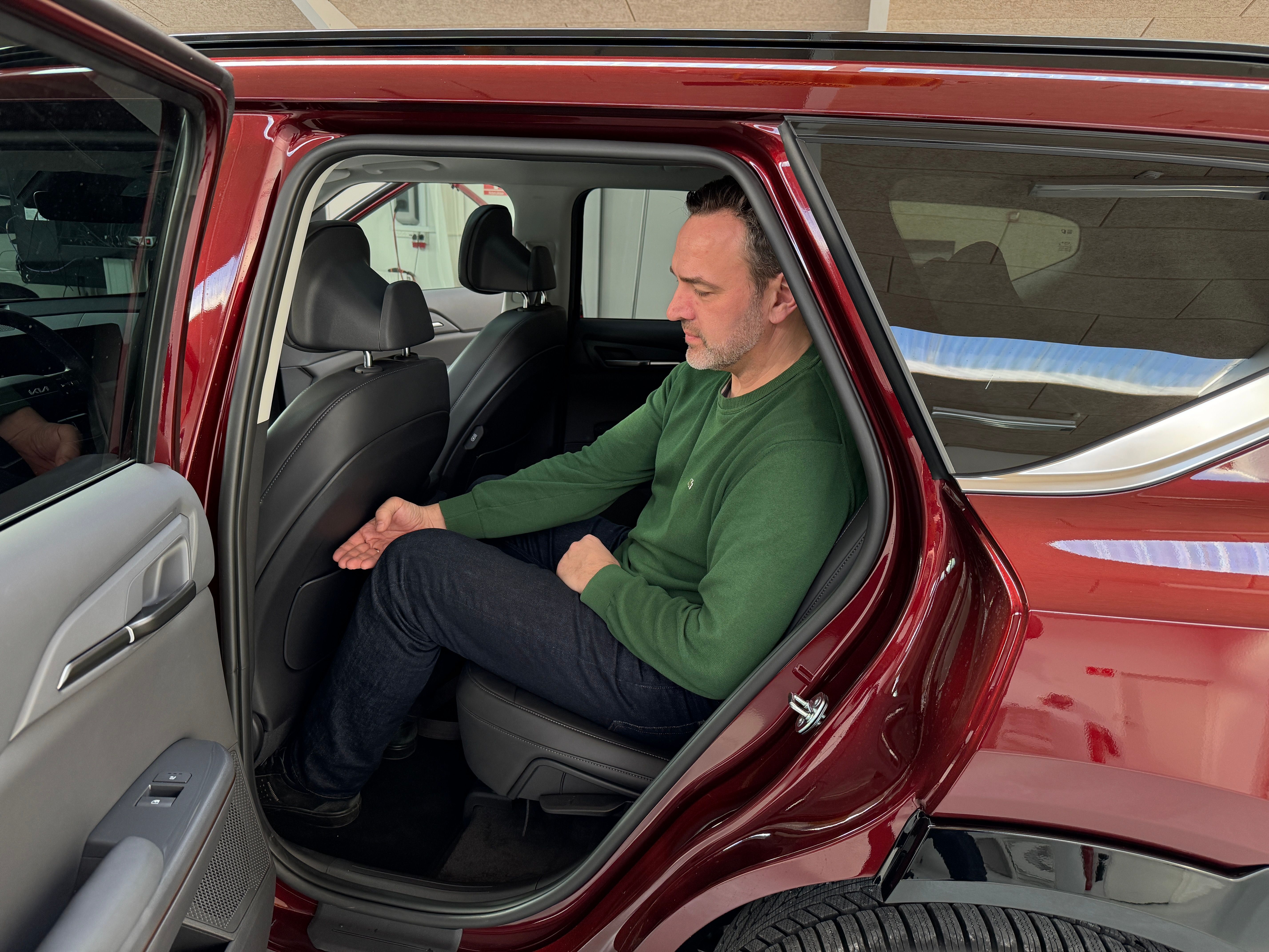 Bagsæde i Kia EV5 hvor der sidder en person med grøn trøje og blå bukser. 