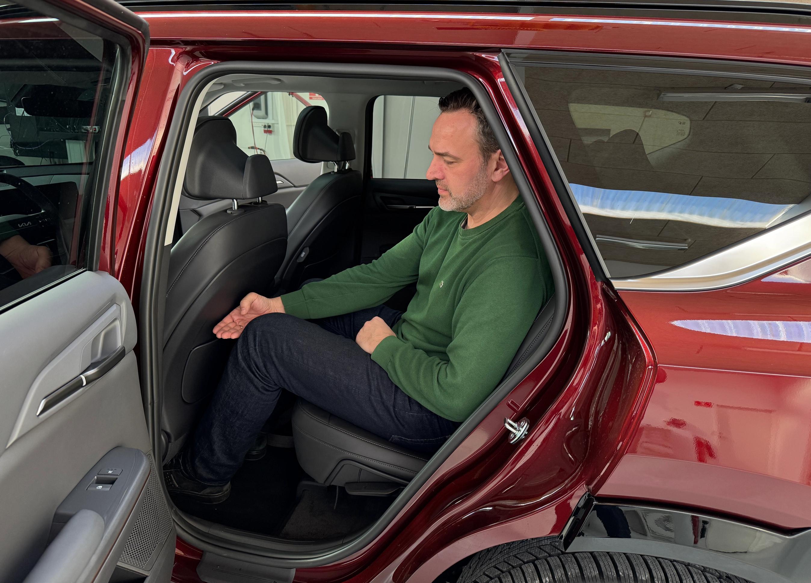 Bagsæde i Kia EV5 hvor der sidder en person med grøn trøje og blå bukser.