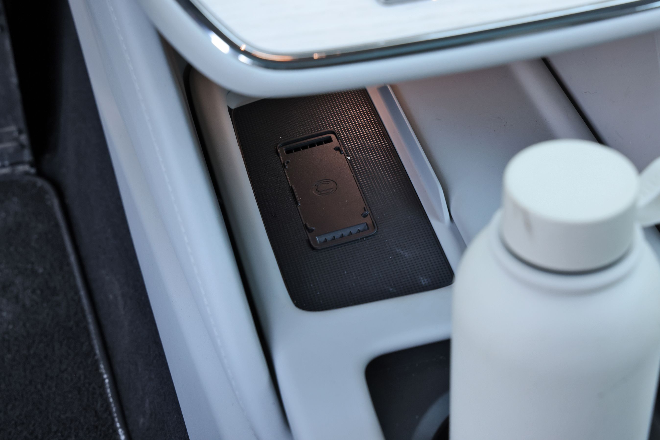 Mobillader i en Volvo ES90 med drikkeflaske i forgrunden