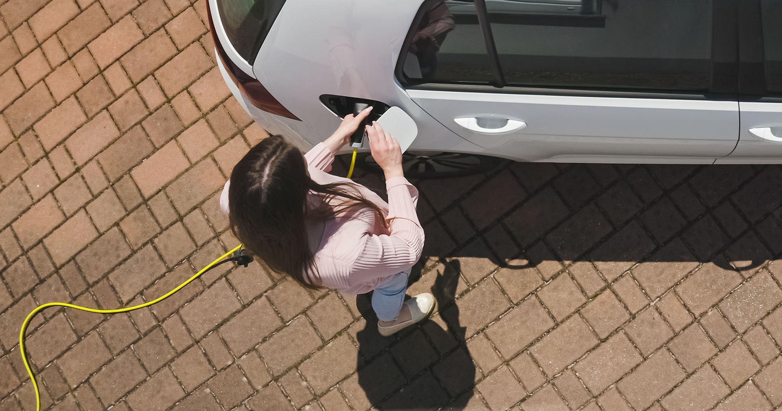 Kvinde lader en elbil udenfor.