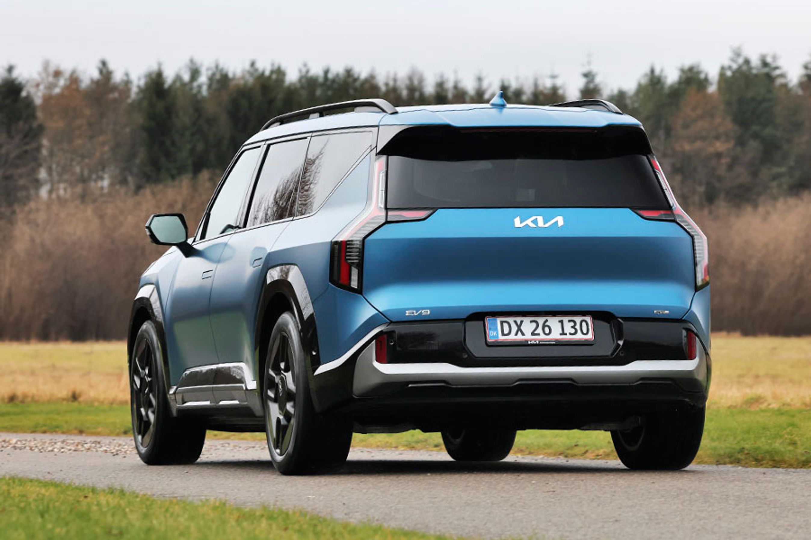 Blå Kia EV9 set bagfra, mens den kører på landevej