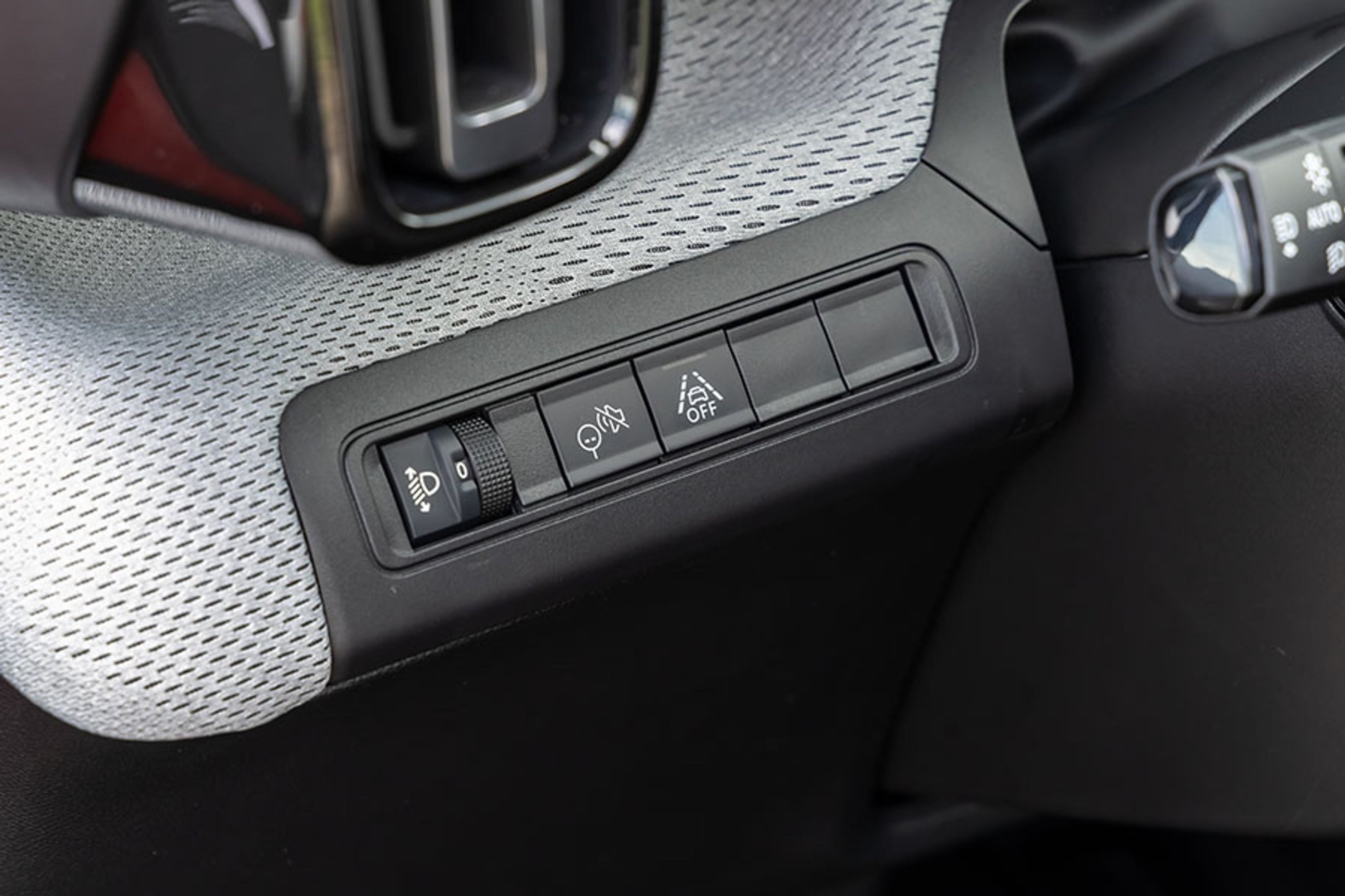 Til venstre for rattet er der tre vigtige knapper. Fra venstre er det en knap til regulering af lysvidden, dernæst en knap til at slå alarmen for hastighedsoverskridelsen fra og endelig en knap til at frakoble vejstribealarmen.