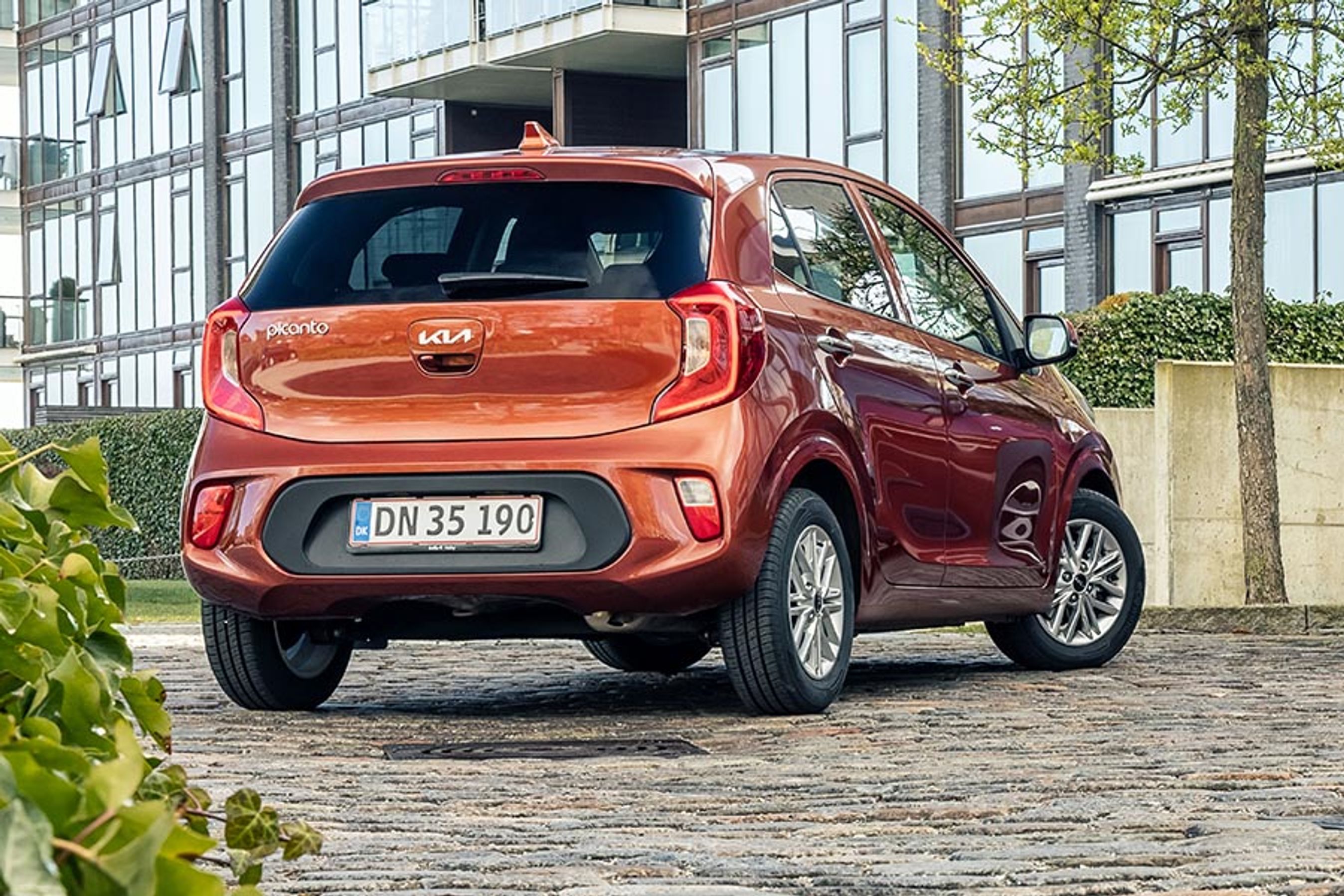 Kia Picanto set bagfra holder på brosten med grønt i forgrunden.