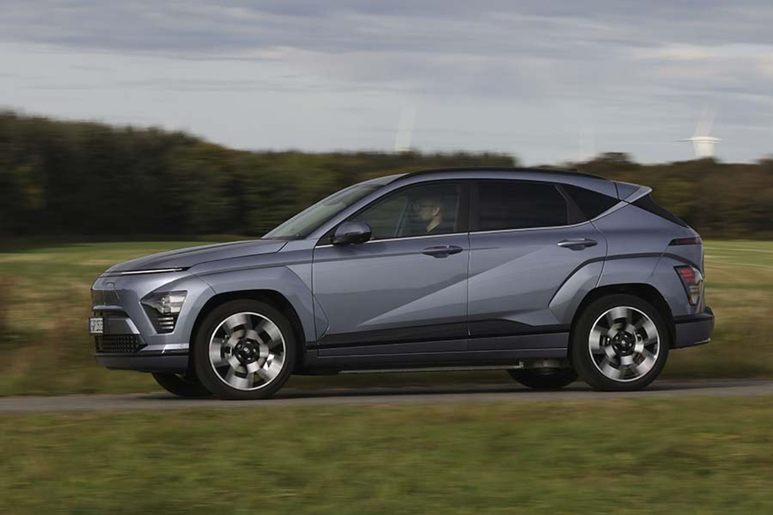 En Hyundai Kona set fra siden, mens den kører på en landevej.