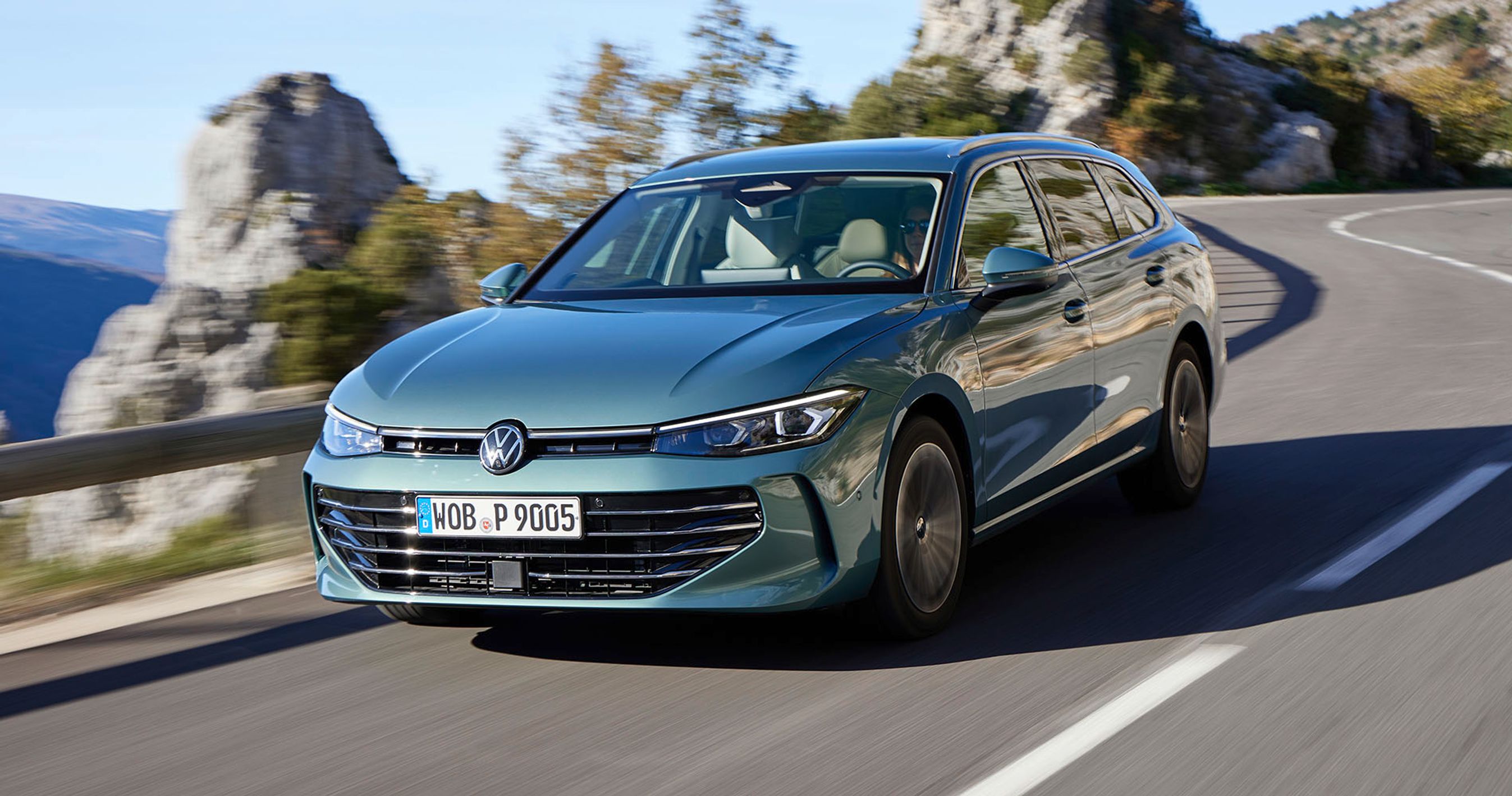 En blå VW Passat kører i et sving på en kystvej med havet i baggrunden.