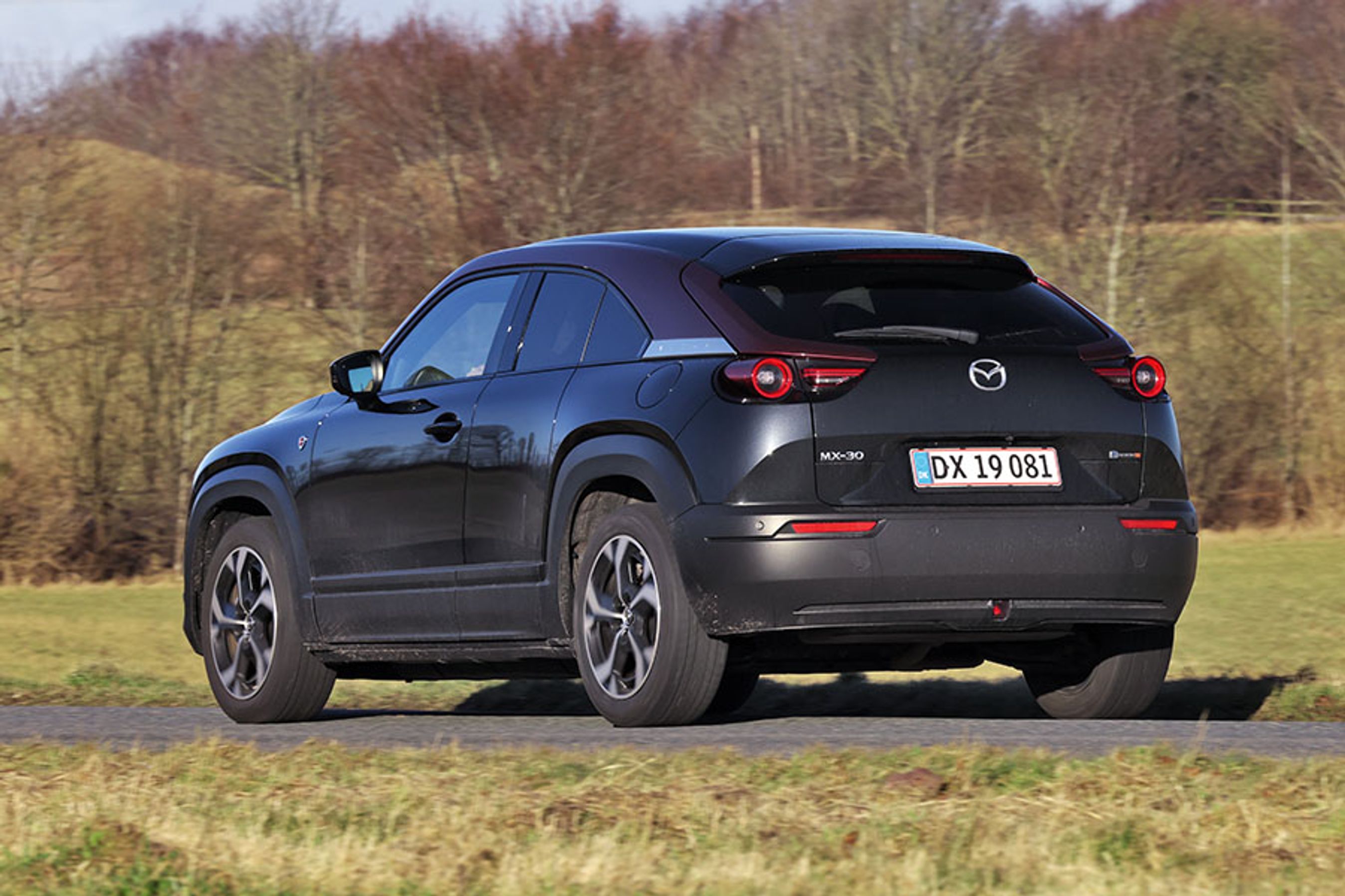 Sort Mazda MX-30 set bagfra kører på en vej