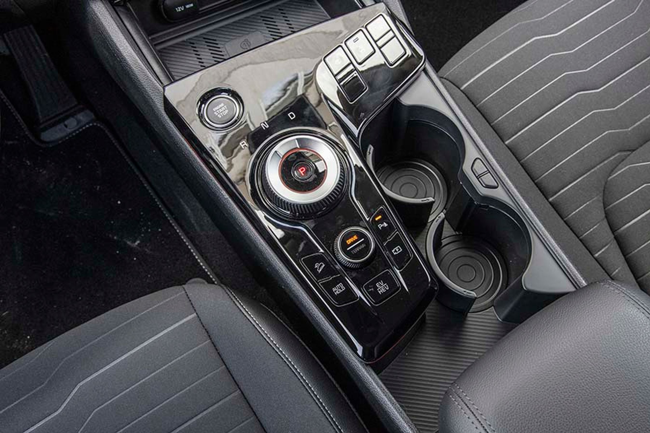 Mellem forsæderne er den store drejeknap, der styrer kørselsretningen på en meget intuitiv måde. En knap skifter mellem hybriddrift og ren eldrift på kortere ture, mens et par store kopholdere er en rar detalje på længere ture.