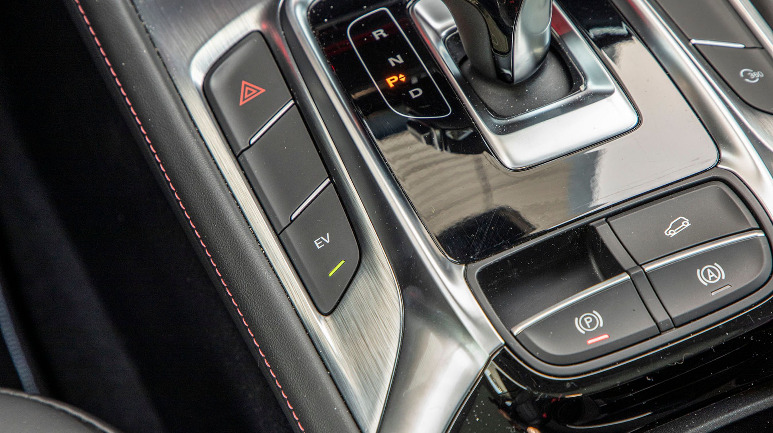 Den lille EV-knap til venstre for gearstangen skal trykkes ned, hvis man vil køre på el. Men ofte bestemmer bilen sig selv for igen at køre på benzin, og så skal den trykkes ned efter kort tid, hvis man igen hellere vil køre udelukkende på el.