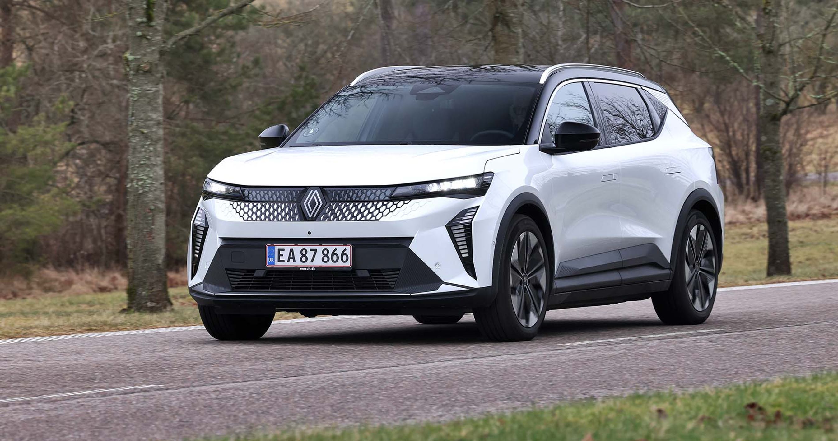Renault Scenic set skråt forfra, mens den kører på vej med træer rundt om