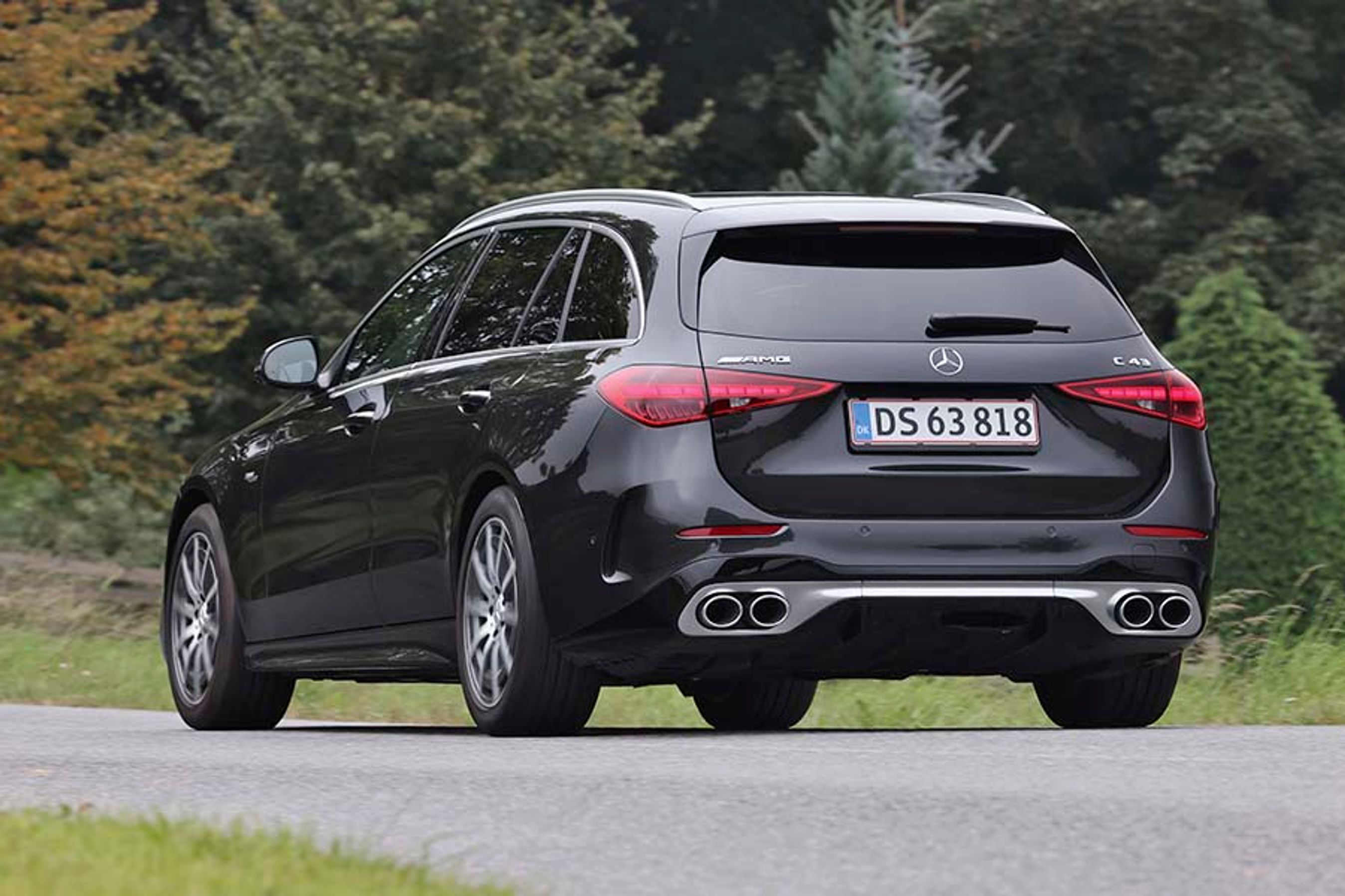 En sort Mercedes-AMG C 43 set bagfra, mens den kører på en landevej.