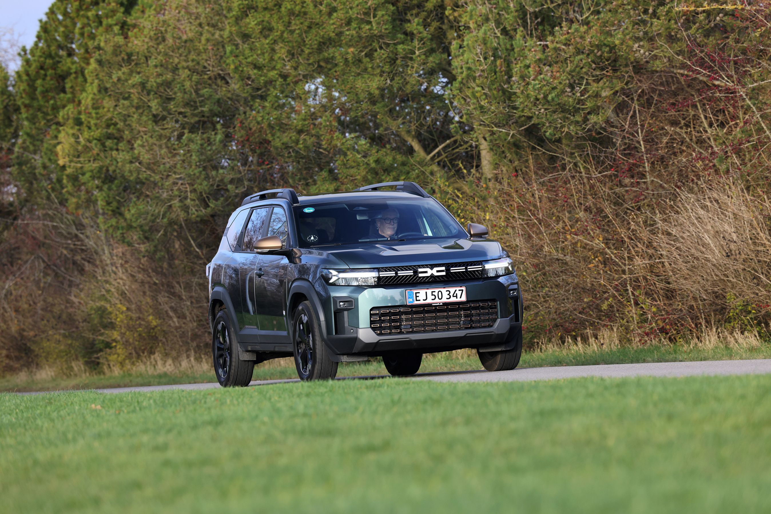 Dacia Bigster set forfra, mens den kører på vej med træer i baggrunden