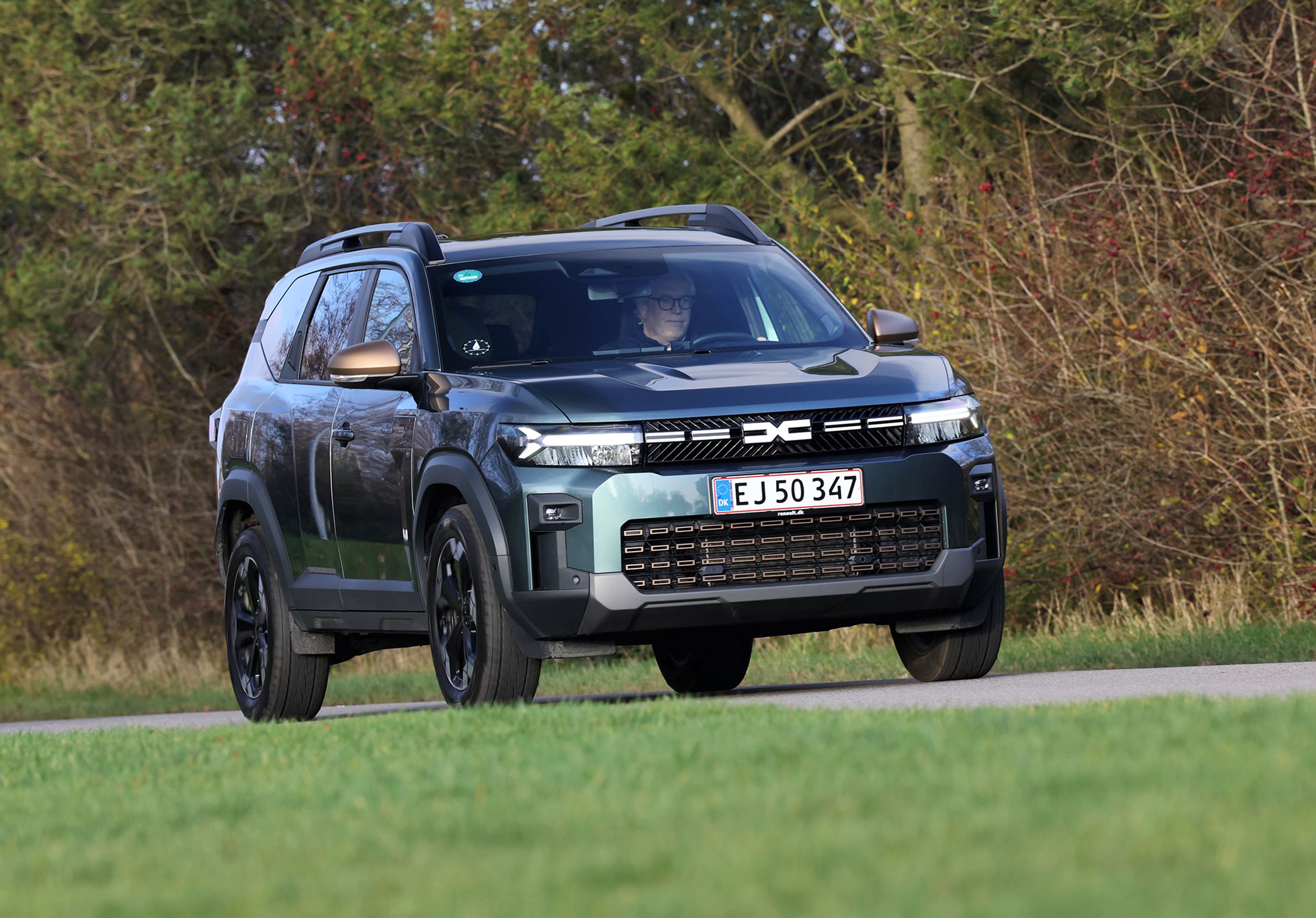 Dacia Bigster set forfra, mens den kører på vej med træer i baggrunden